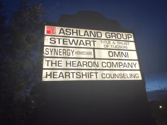 Outdoor signboard at dusk displaying SYNERGY HomeCare among other local business names.