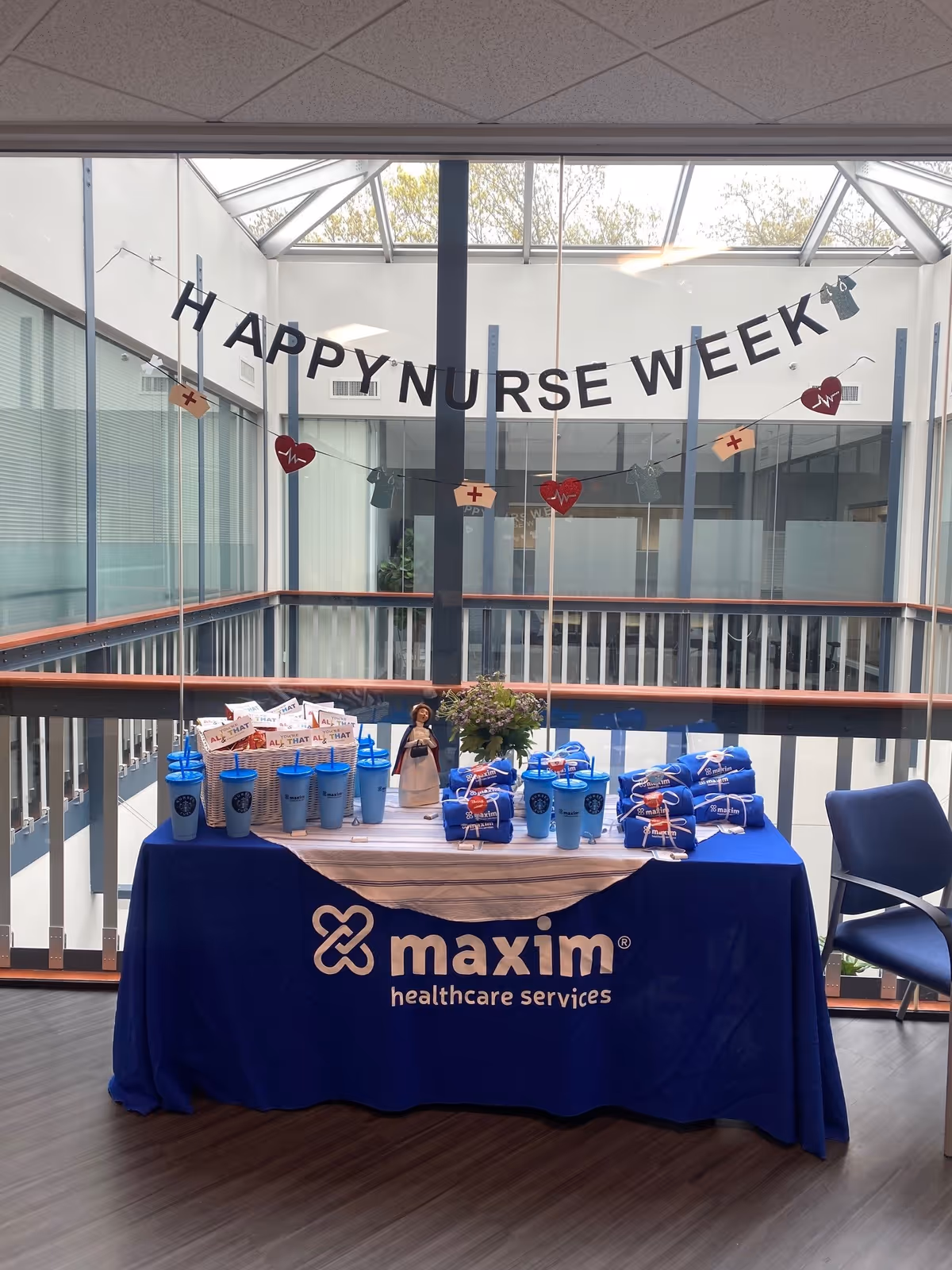 Indoor hallway with a Maxim Healthcare table and a Happy Nurse Week banner.