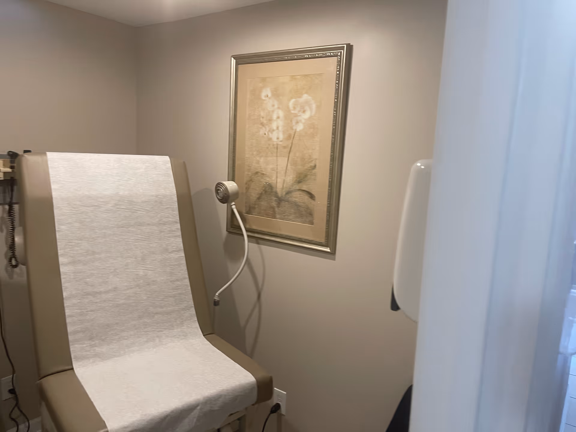 A medical imaging exam room with a large examination table and framed orchid artwork.