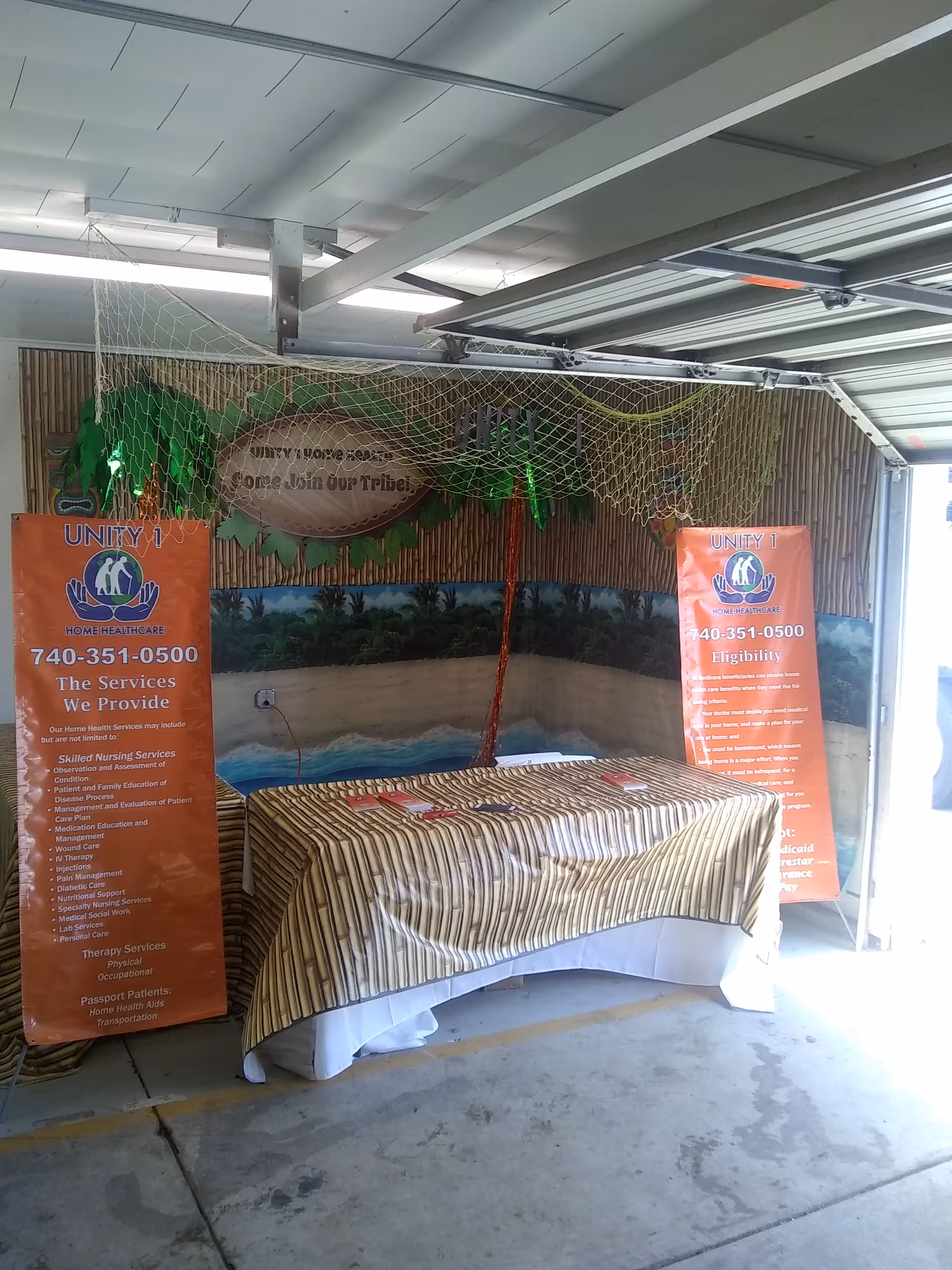 Promotional booth for Unity 1 Home Health Care inside a garage-like interior.