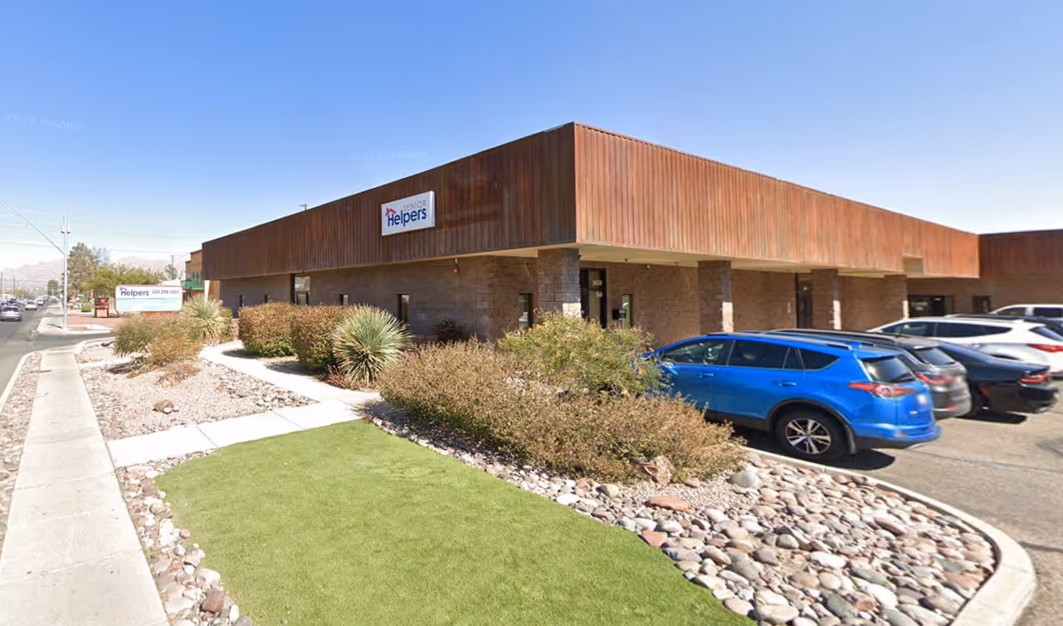 Exterior view of a Senior Helpers facility with brown facade, landscaping, and parked cars.