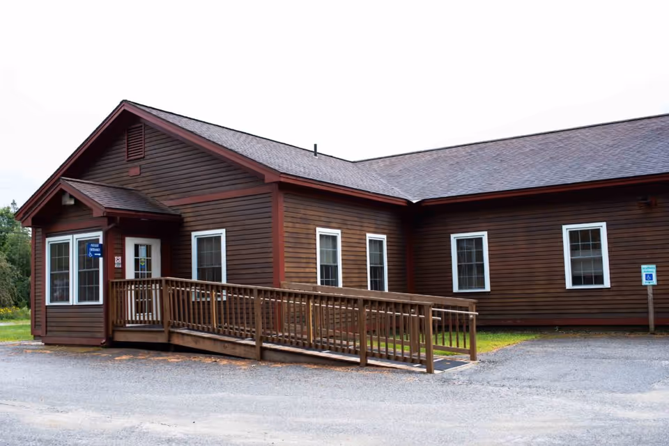Exterior view of a brown wooden senior living facility with a ramped entrance.