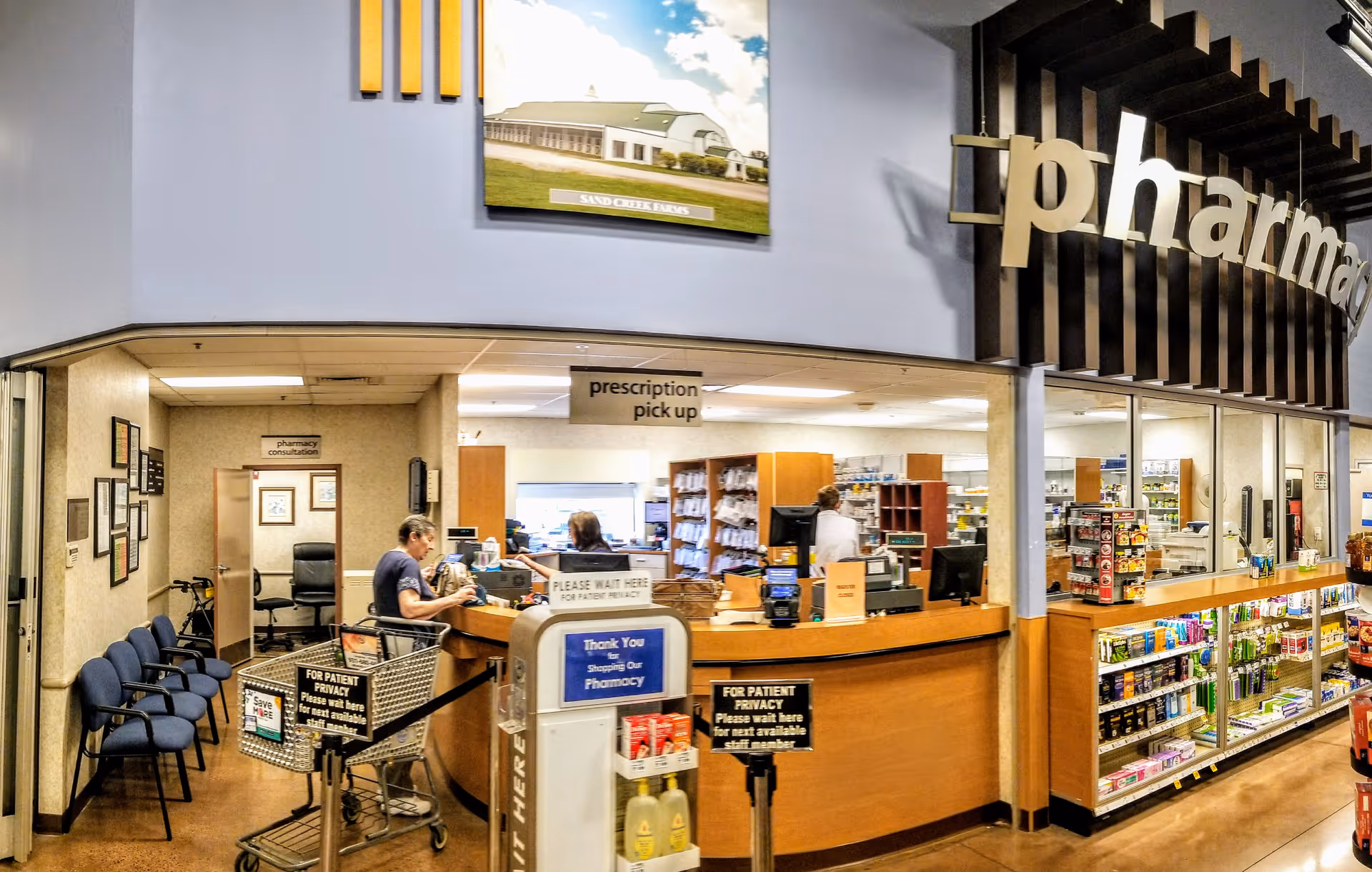 Interior view of a Kroger Pharmacy counter with staff, customers, and pharmacy shelves.