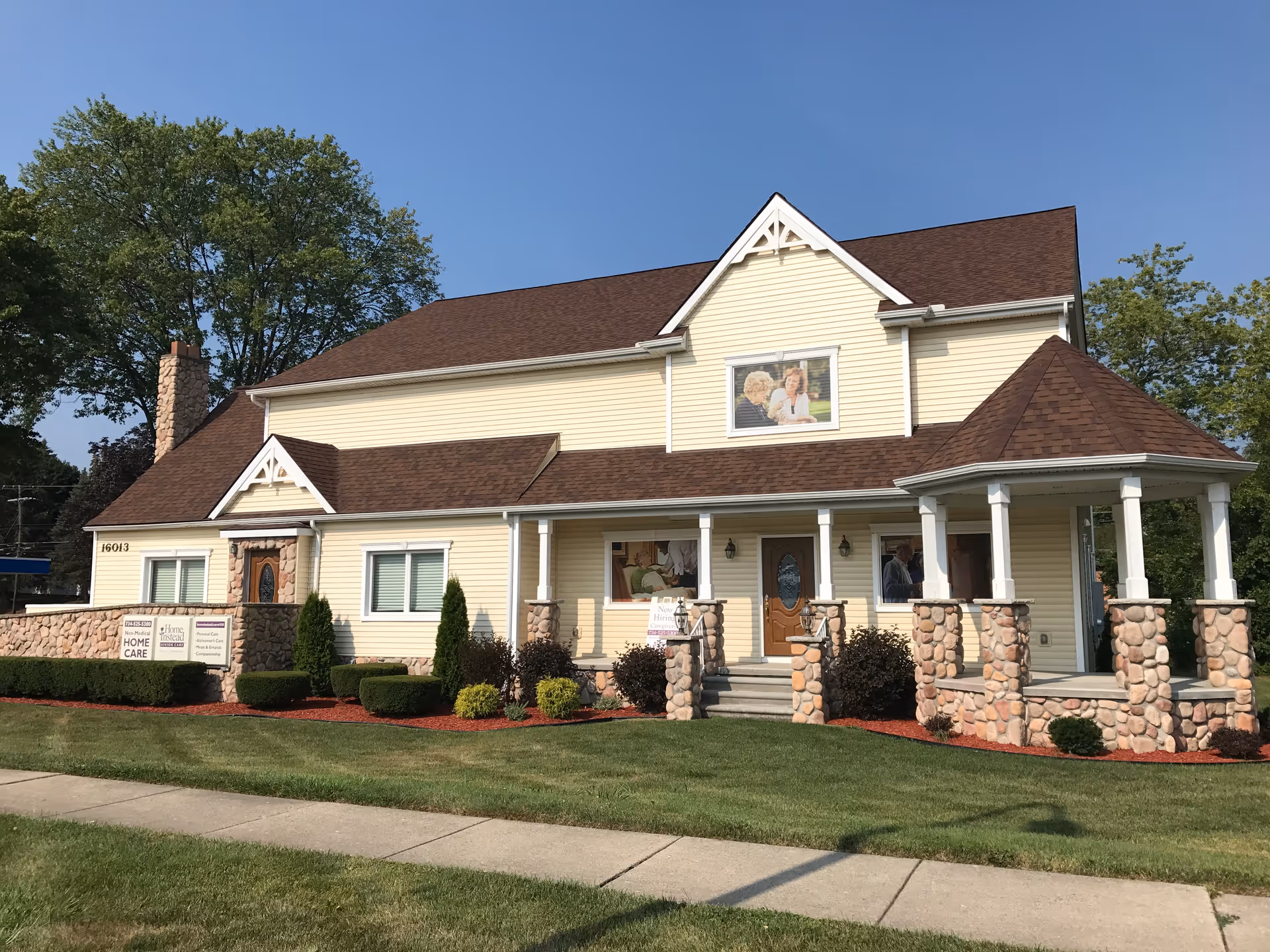 A beige senior living facility with a stone-columned porch and landscaped lawn.
