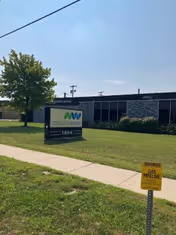 Exterior view of MobilityWorks facility with a sign on a grassy lawn and sidewalk.