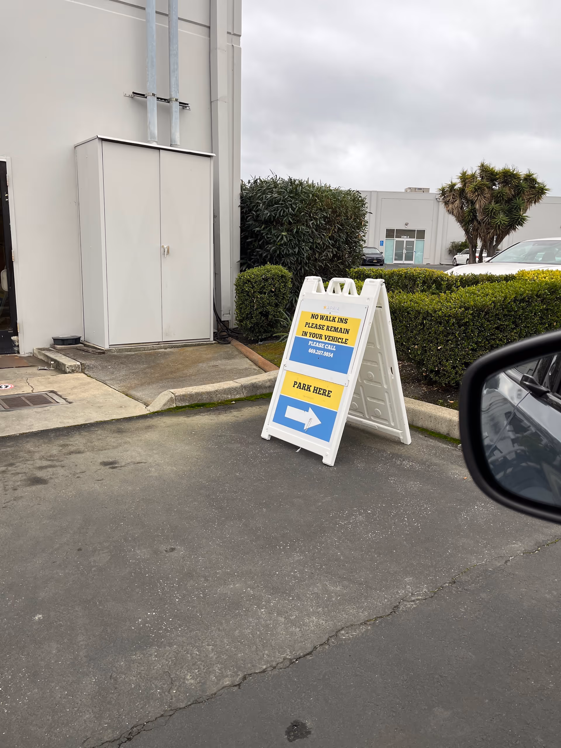 Outdoor view of Apria Healthcare facility exterior with a large signboard near parking.
