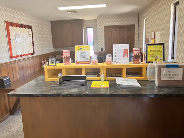 Front desk reception with brochures inside a patterned-walled senior facility interior.