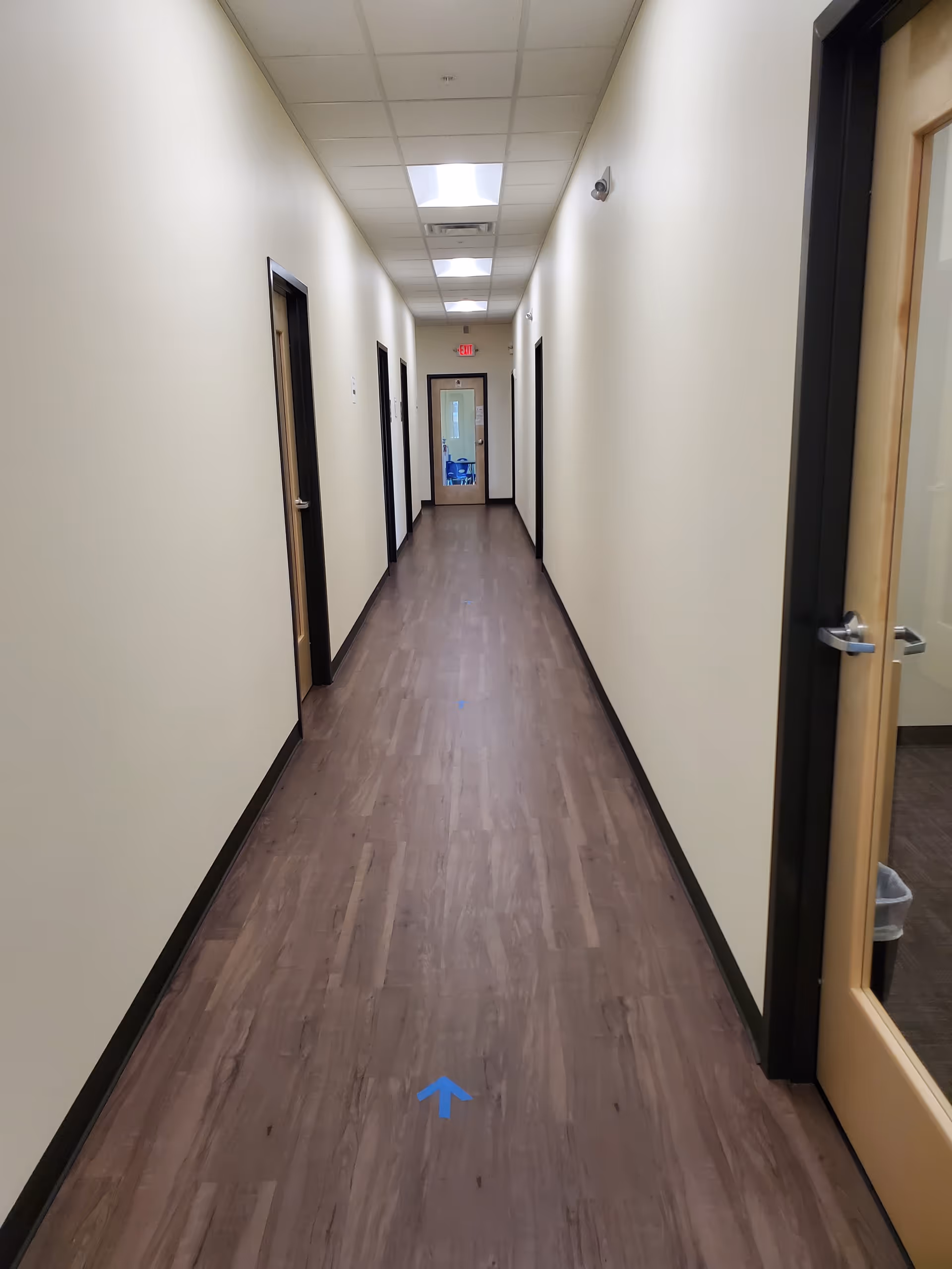 Long hallway inside a facility with closed doors along both sides and overhead lights.