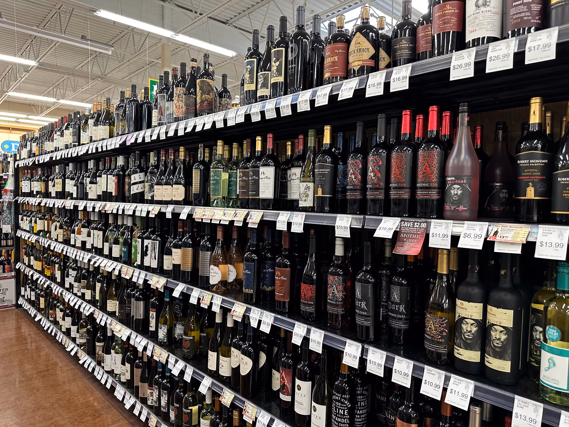 Aisle of wine bottles on shelves with price tags inside Discount Drug Mart.