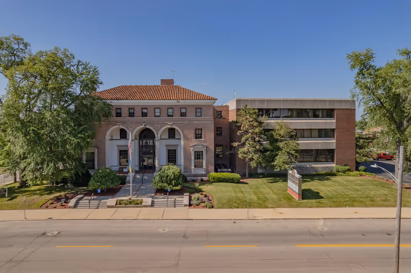 Exterior view of Healthcare Plus Caregivers building with brick arches and manicured lawn.