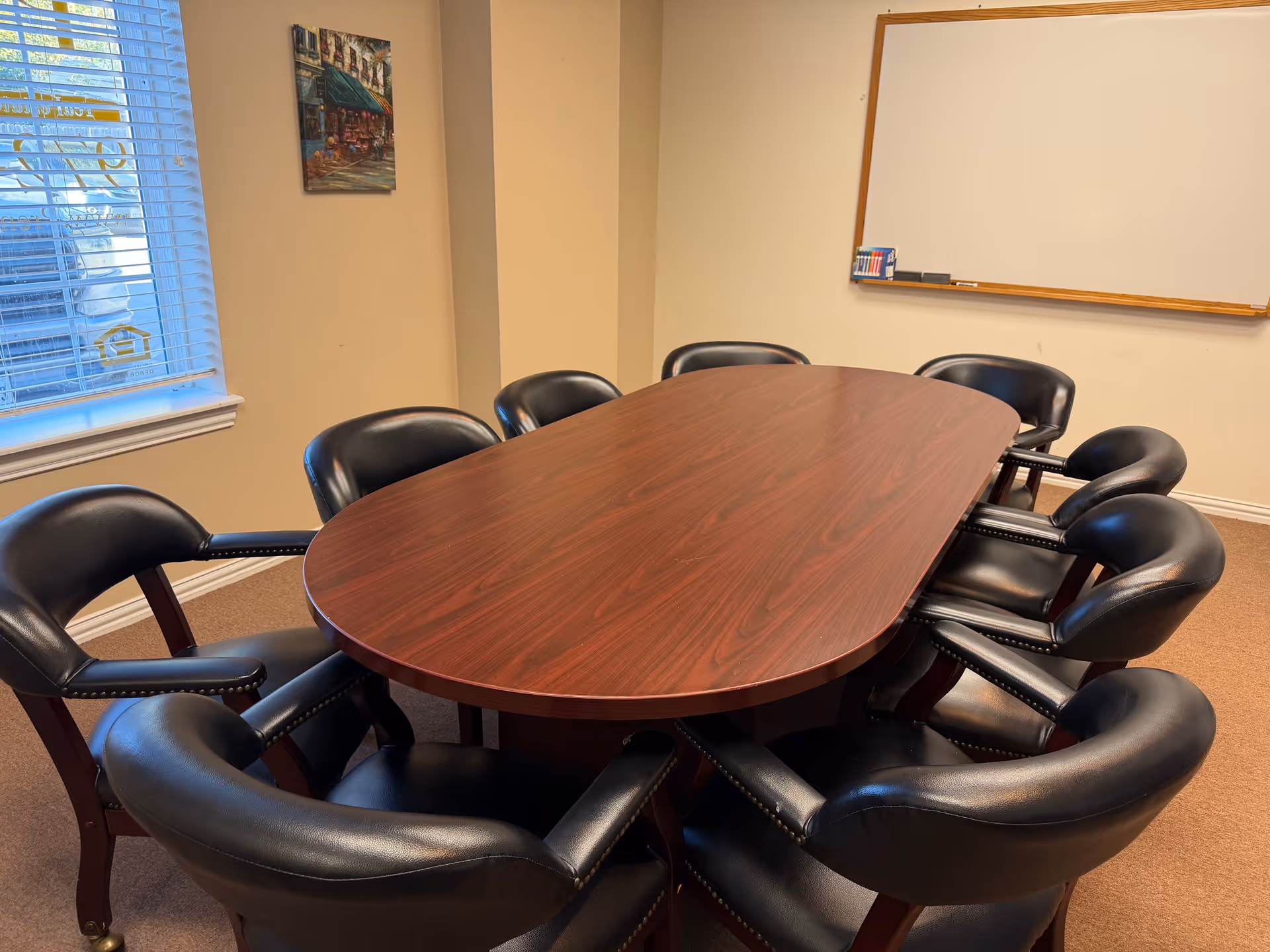 Interior meeting room with an oval wooden table and black leather chairs.