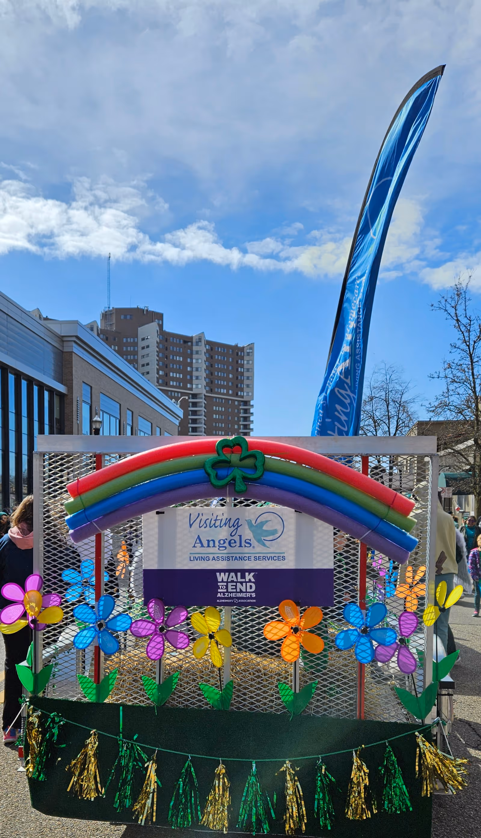 Outdoor parade float for Visiting Angels in Plainwell featuring a rainbow arch and flowers