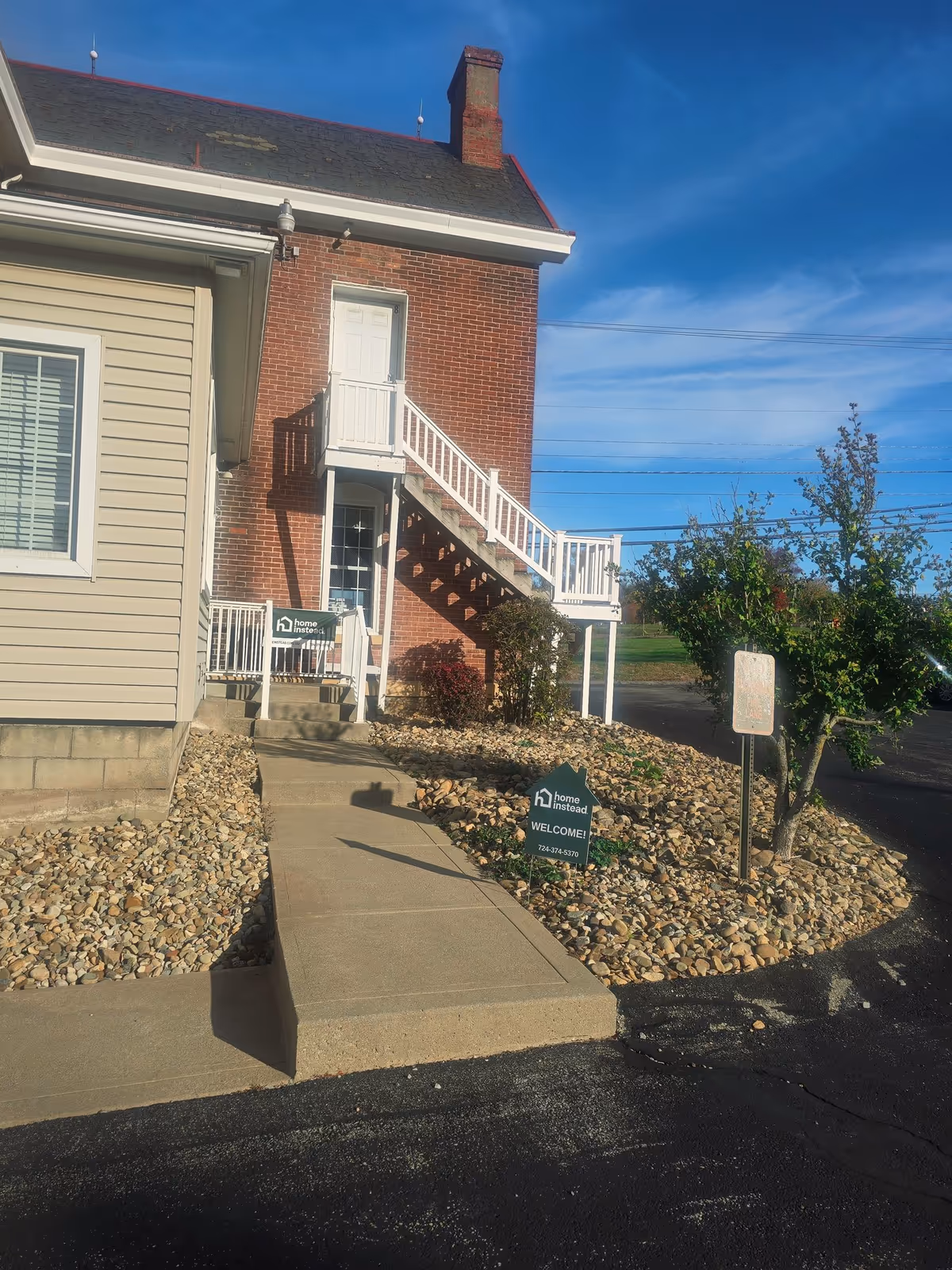 Exterior view of a brick senior facility with stairs, ramp, and a welcome sign.