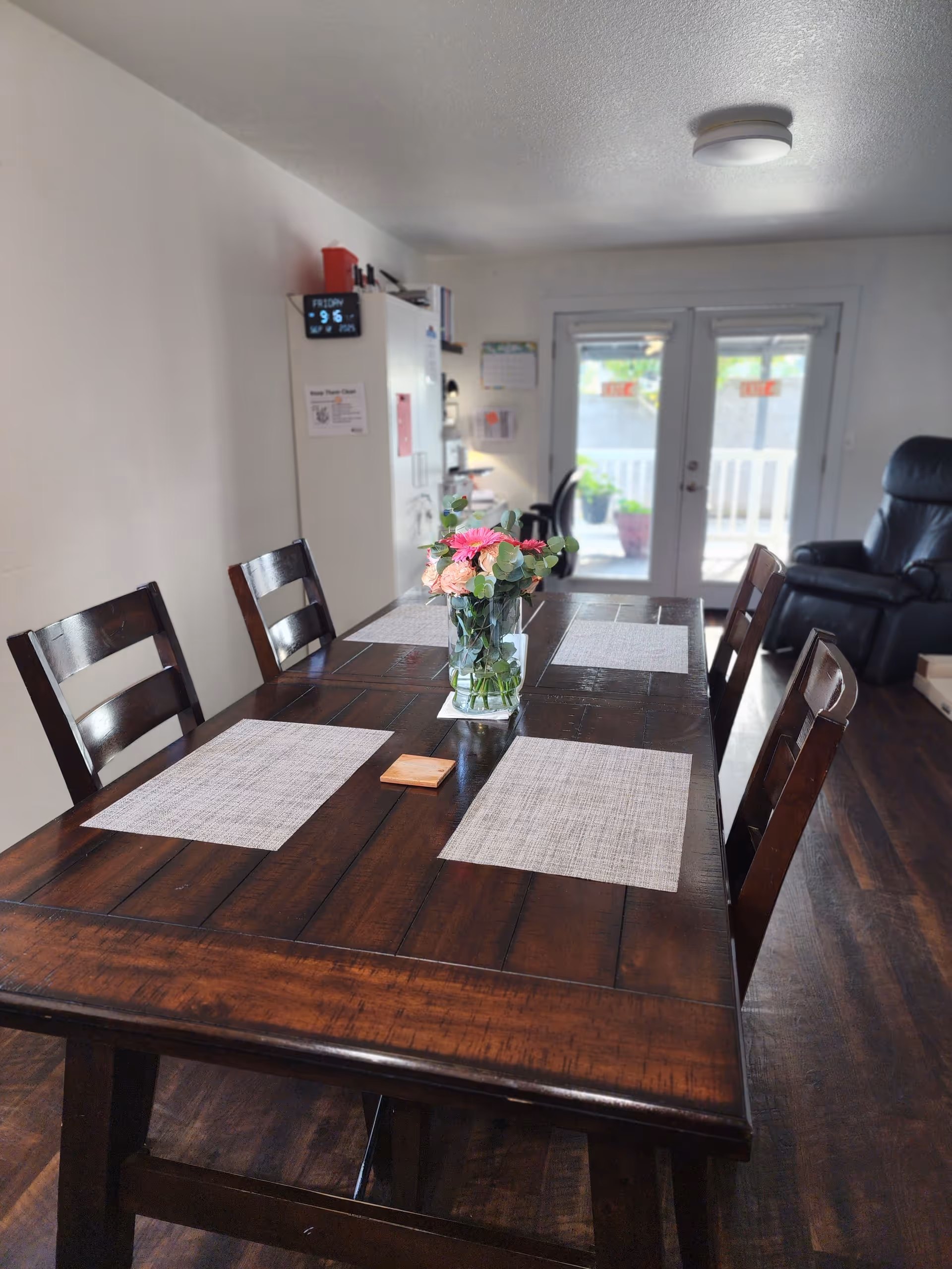A wooden dining table with a vase of flowers in a bright dining room.