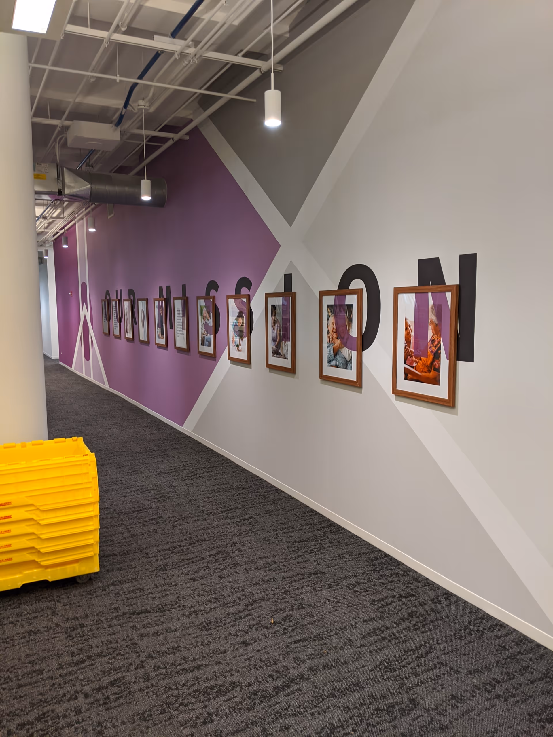 Colorful hallway with framed photos along a purple and light gray wall.