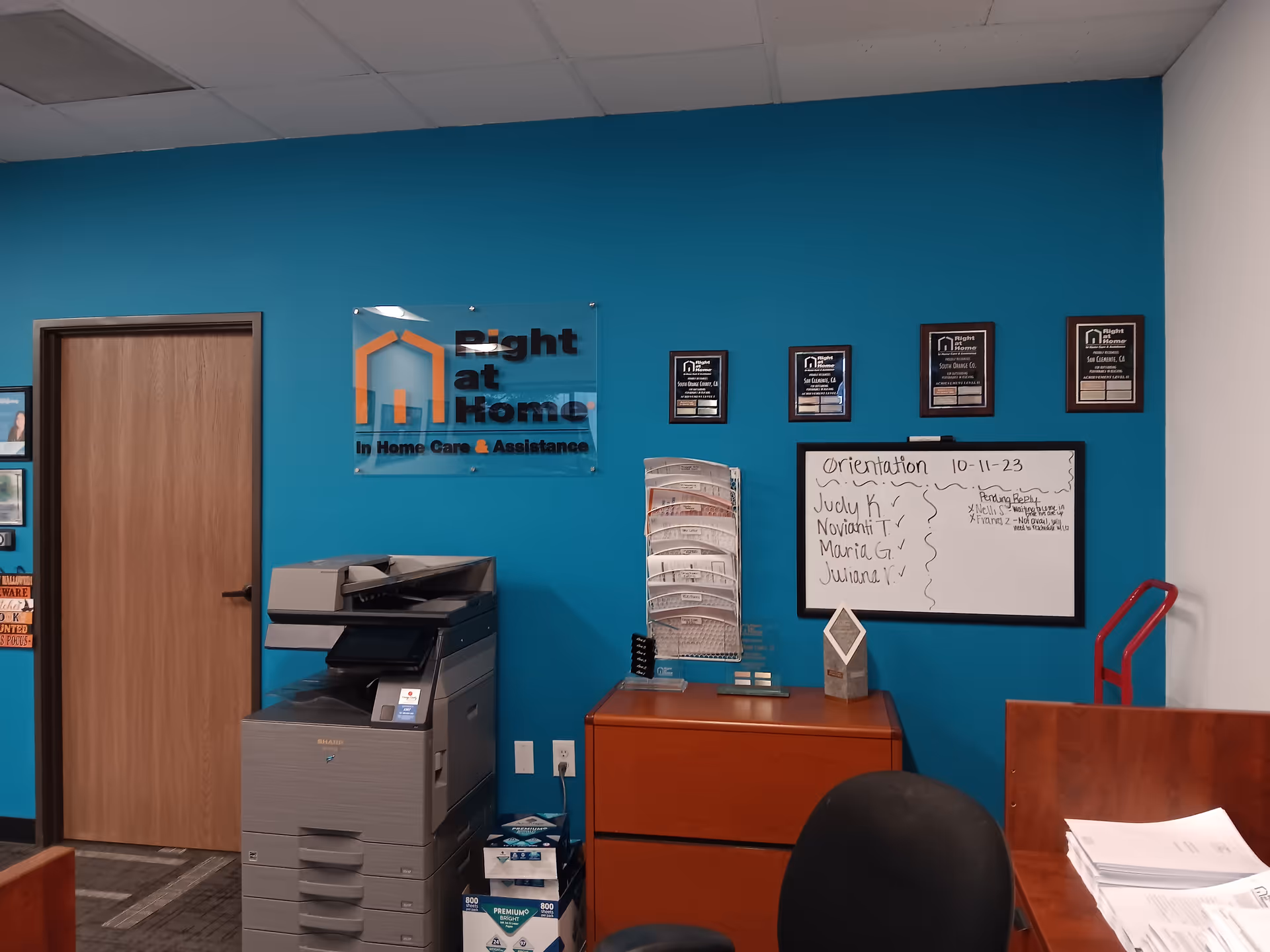 Interior reception area with blue wall, sign, copier, whiteboard, and filing cabinets.