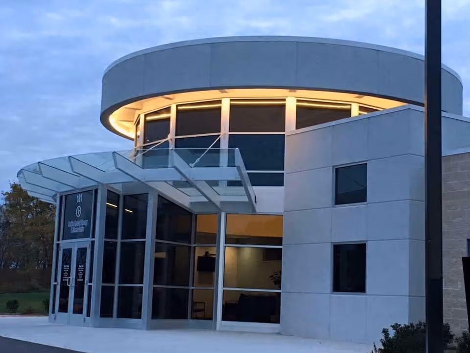Modern senior living facility entrance with glass doors and a curved circular roof.