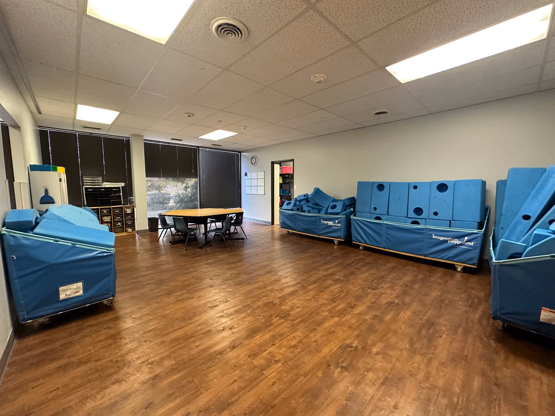 Spacious therapy room with blue foam mats, modular blocks, and a round table.