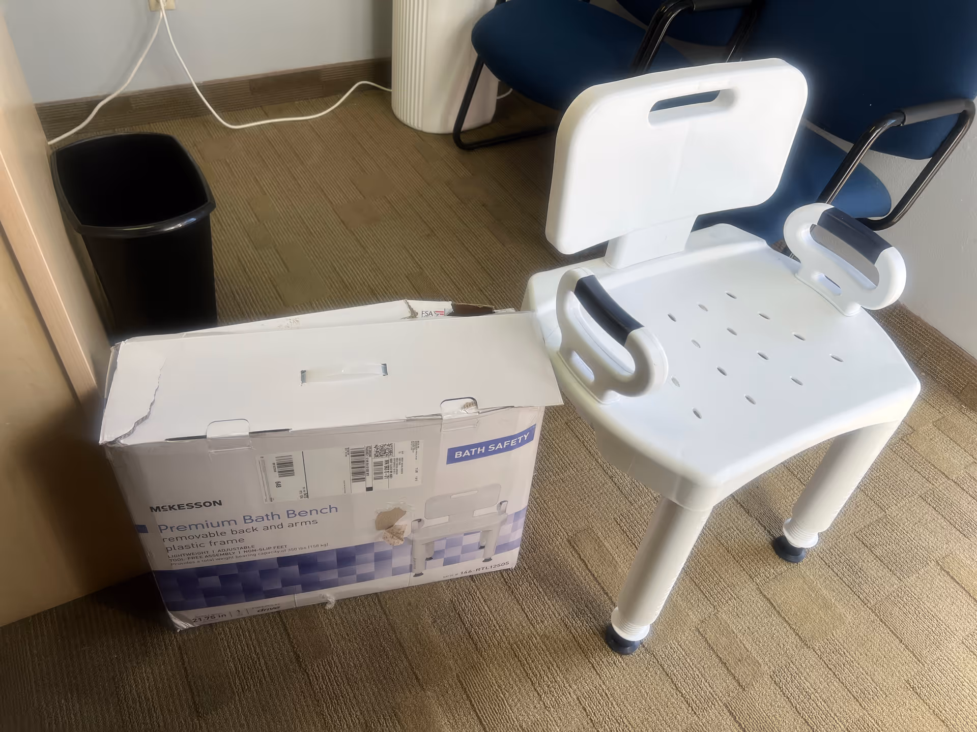 White bath safety chair beside a boxed bath bench in a small room