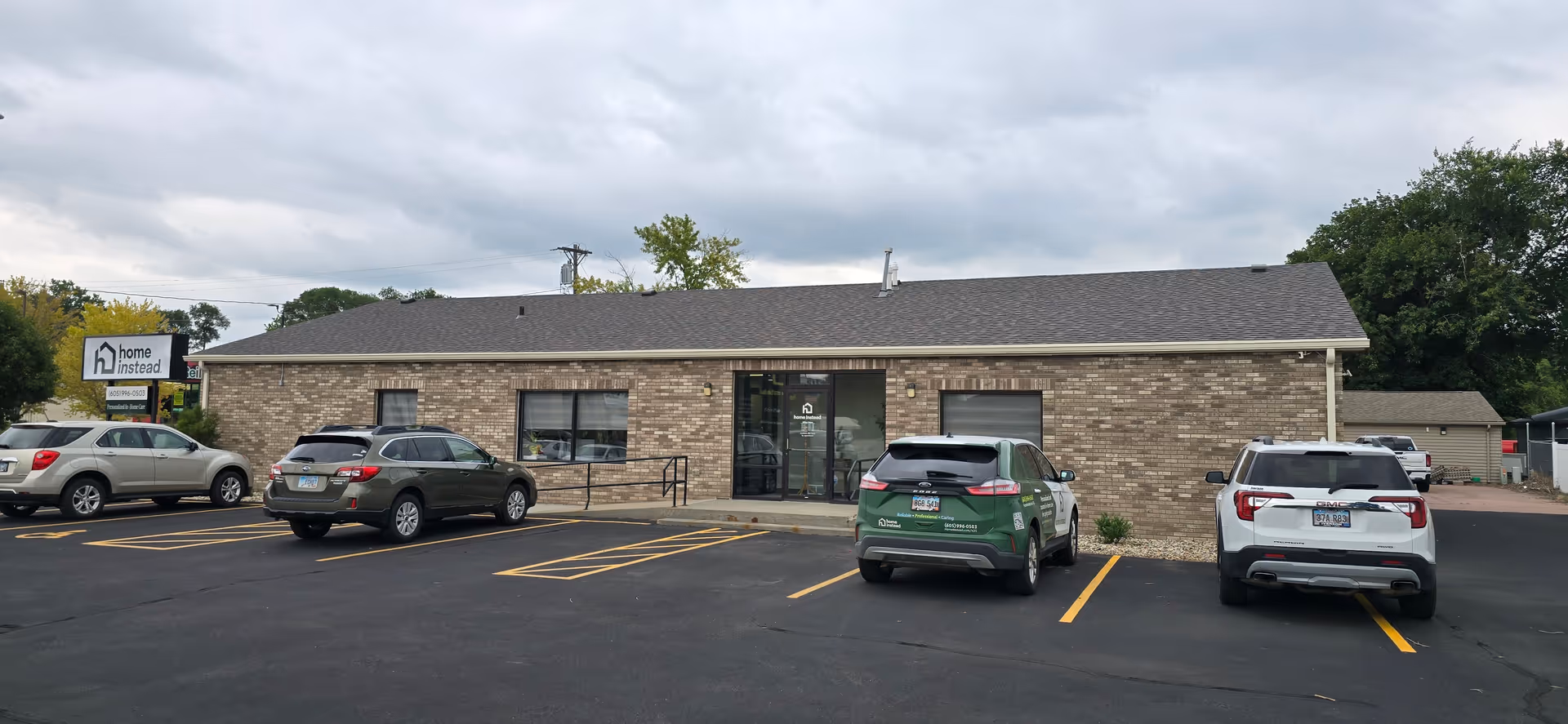 Single-story brick senior living facility with parking lot and Home Instead sign.