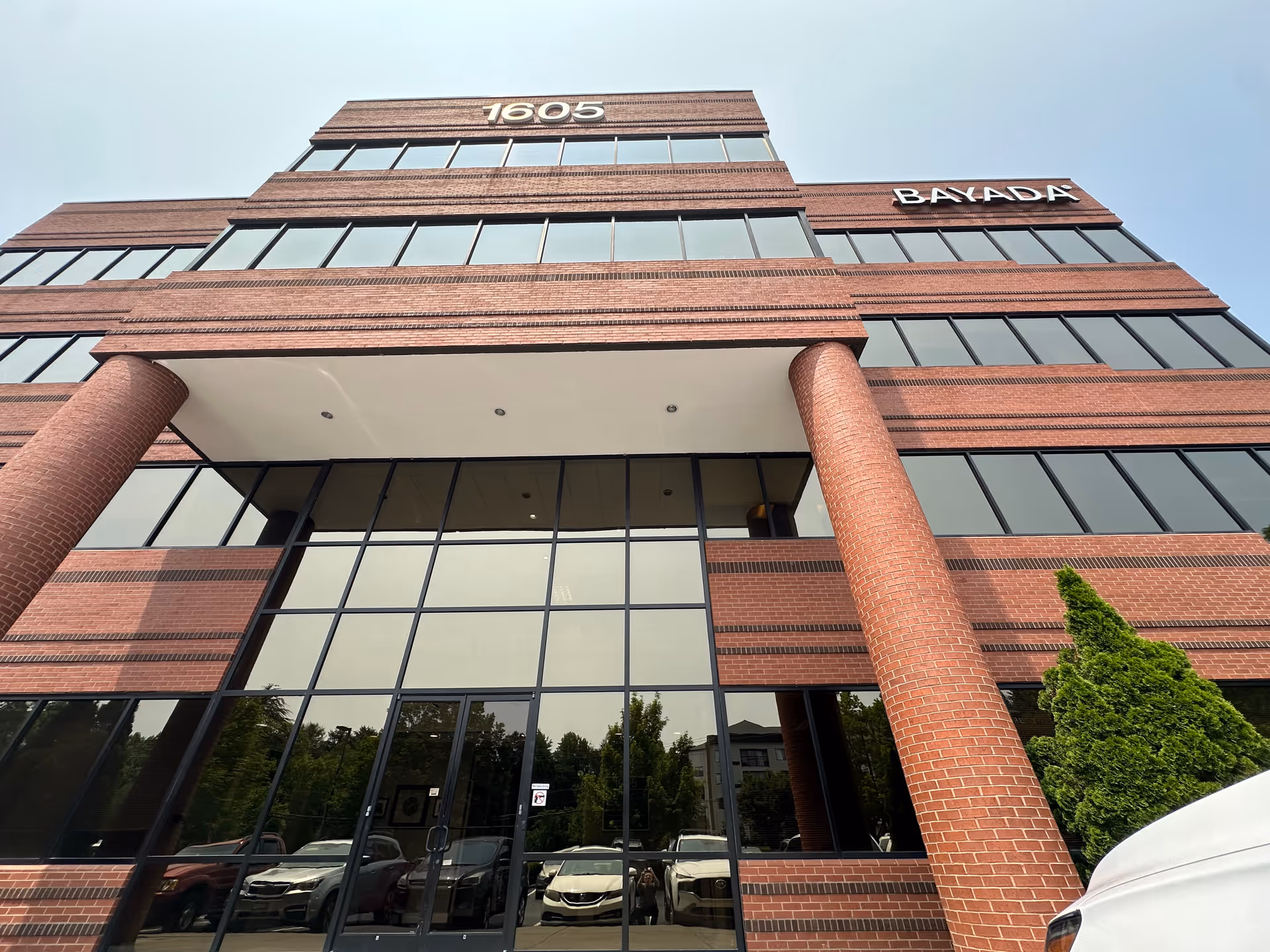 Low-angle view of BAYADA Assistive Care building entrance with glass facade and brick columns.