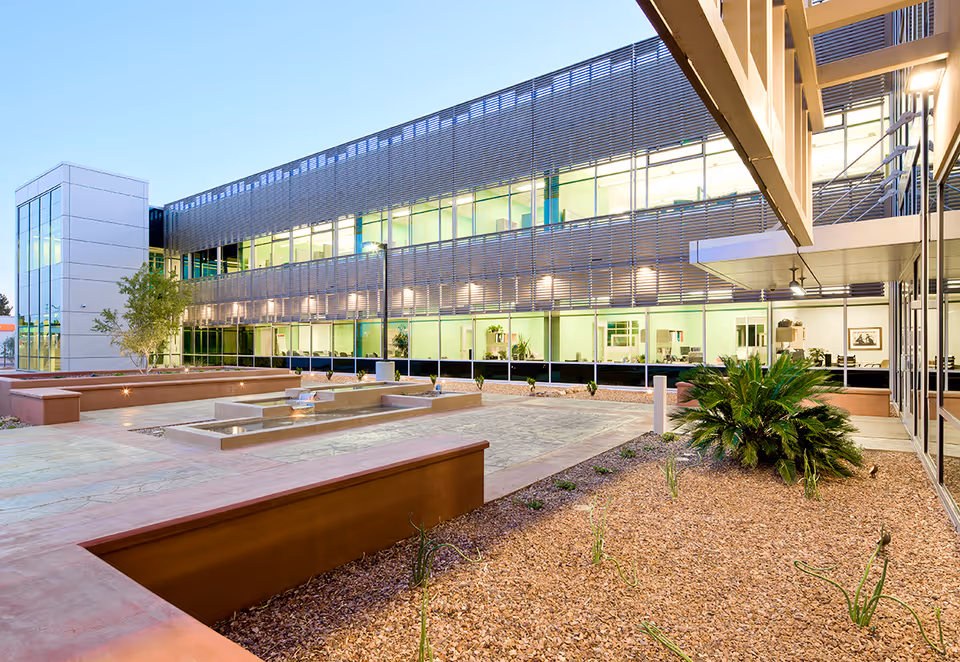 Exterior view of a modern building with a courtyard, planters, and a water feature.