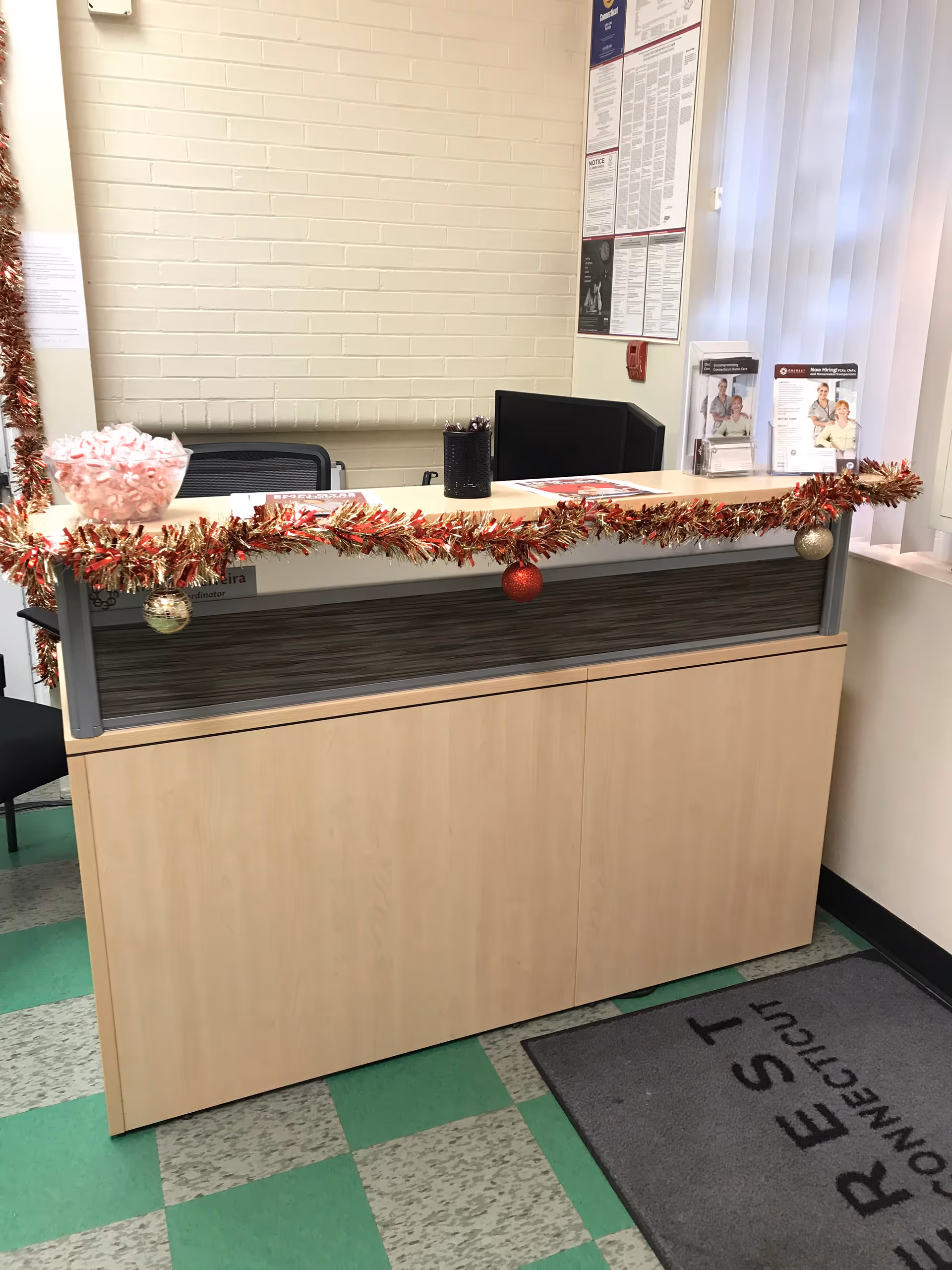 A decorated reception desk inside a facility lobby with garland and ornaments.