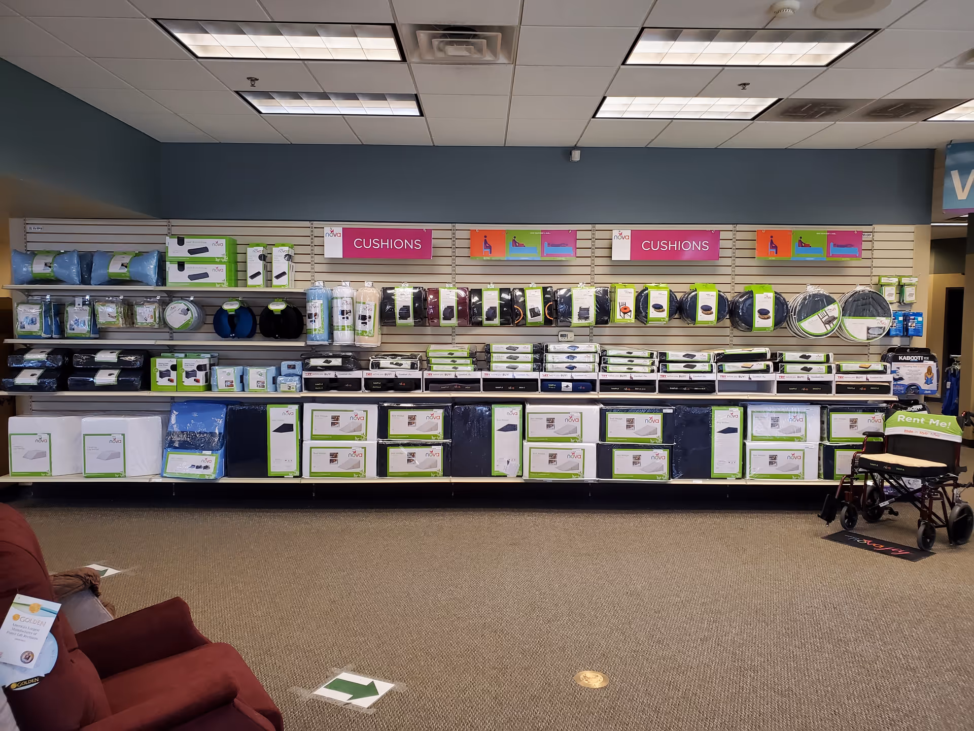Store aisle with medical supplies, cushions, and boxed items on shelves; wheelchair on the right.