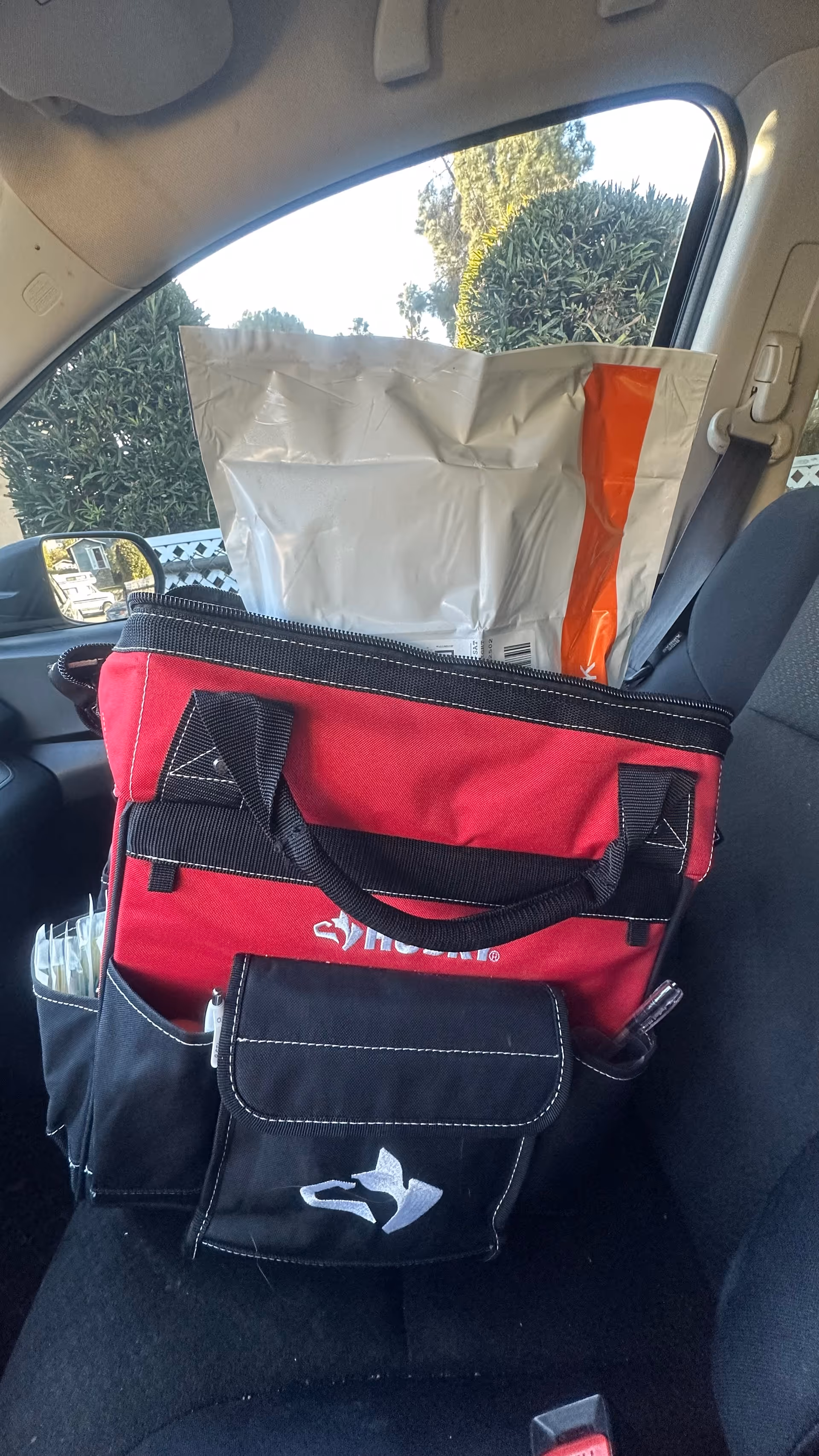 Red medical bag with phlebotomy supplies sits on a car seat.