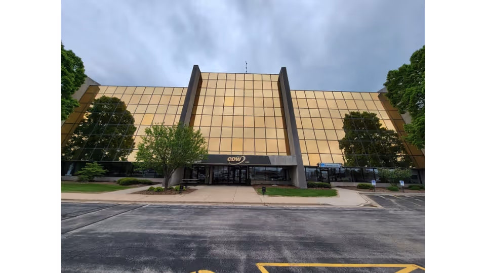 Gold-tinted glass exterior of a large senior living facility with a parking lot.