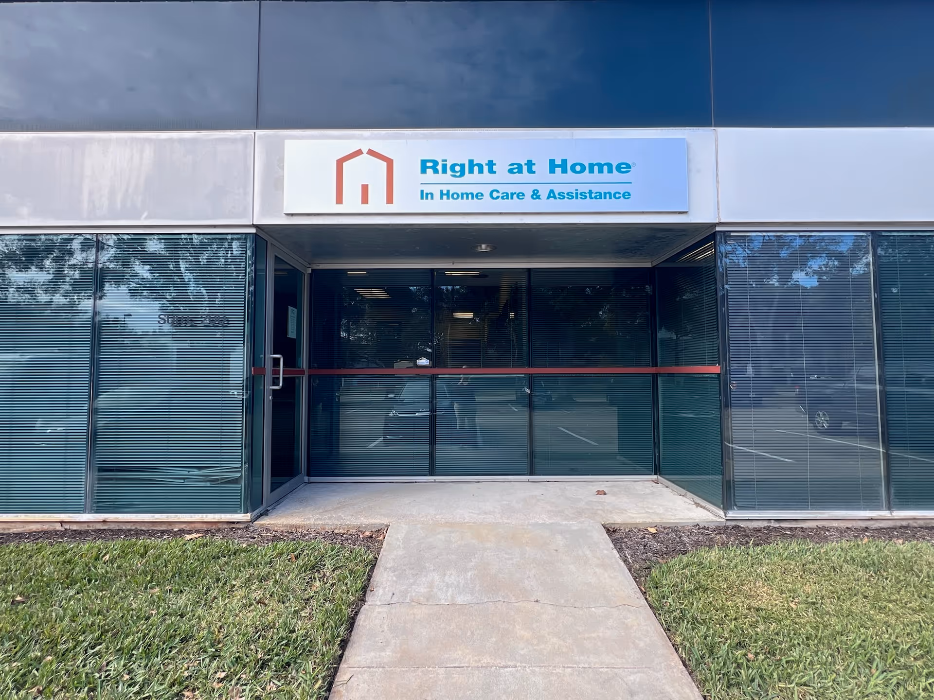 Front entrance of Right at Home facility with glass doors and sign.