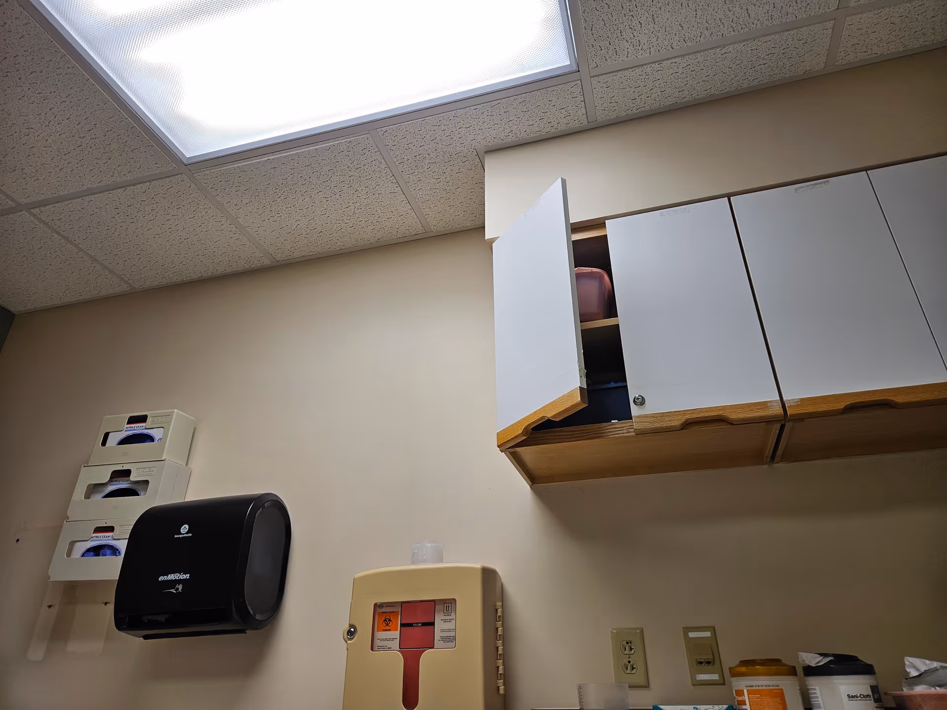 Interior utility room with wall cabinets, a hand dryer, and medical supplies.