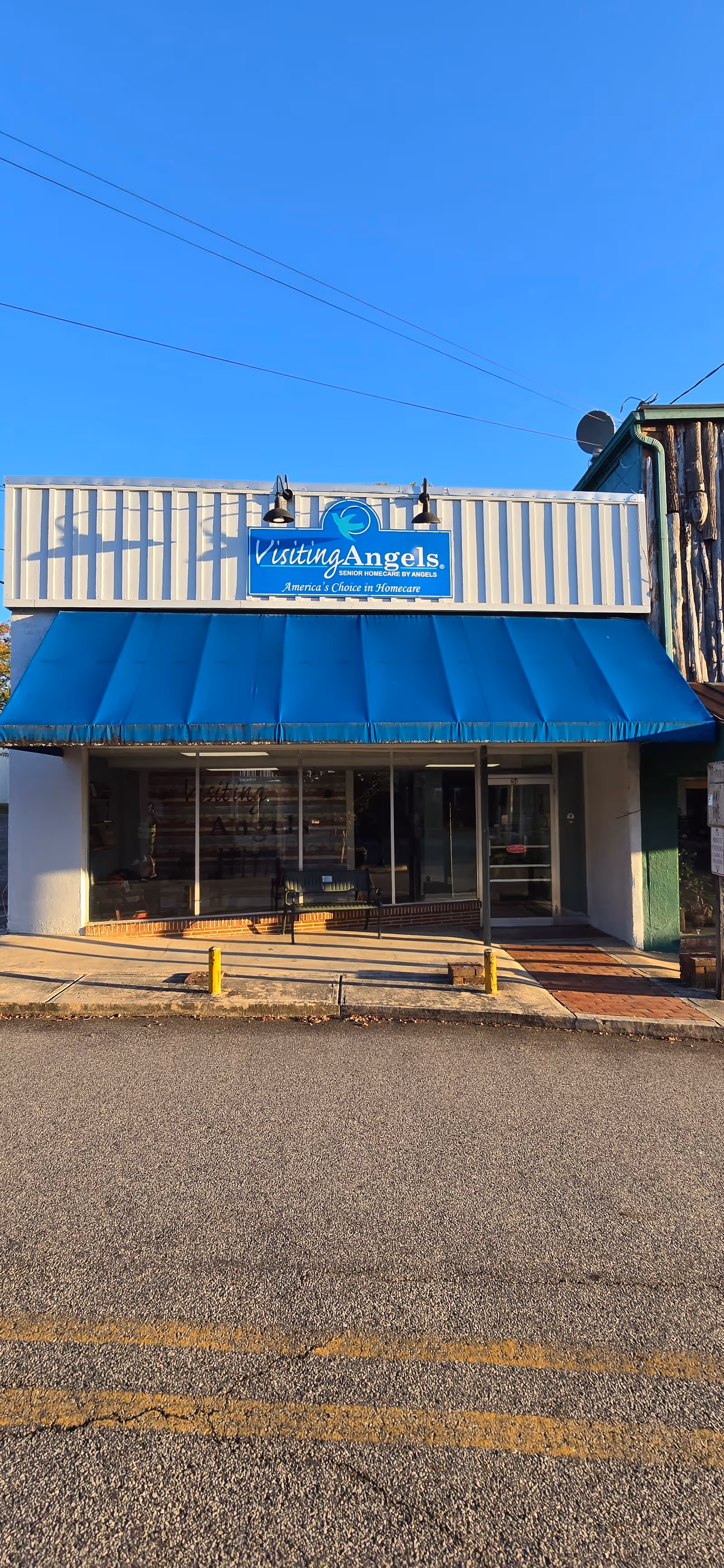 Front view of a Visiting Angels storefront with a bright blue awning.