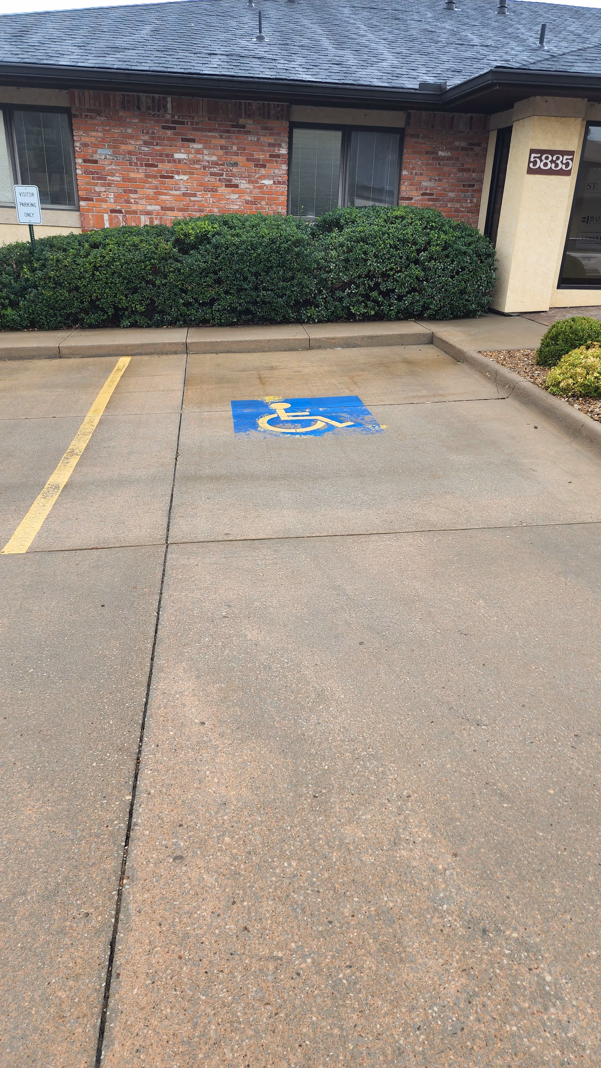 Front exterior of a brick senior living building with a handicapped parking space.