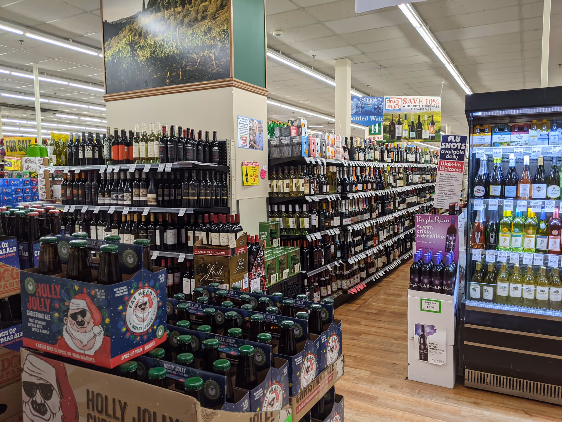 Wide grocery store aisle filled with shelves of wines and spirits, refrigerated section on right.