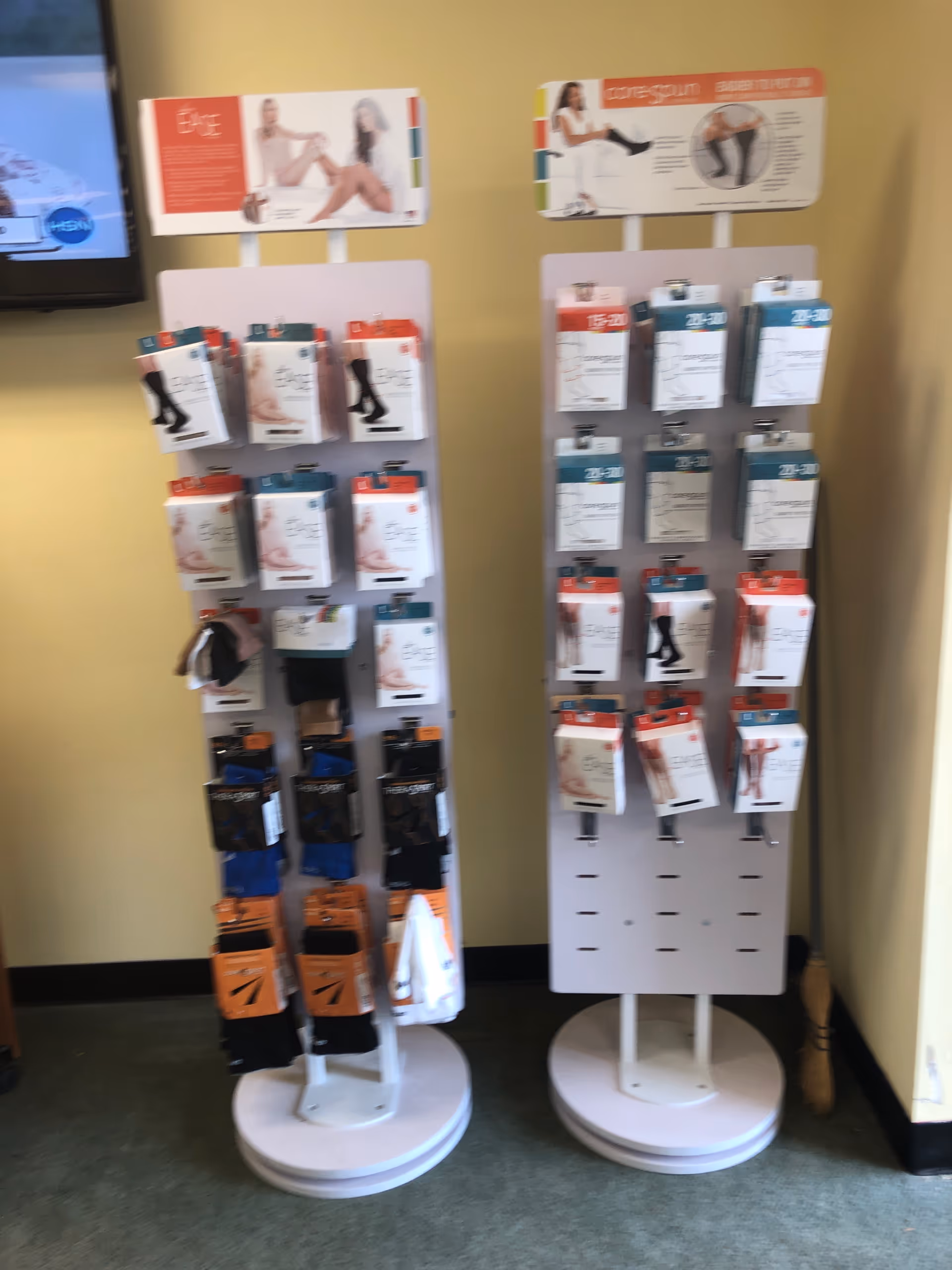 Two white display stands with packaged legwear in a yellow-walled interior.