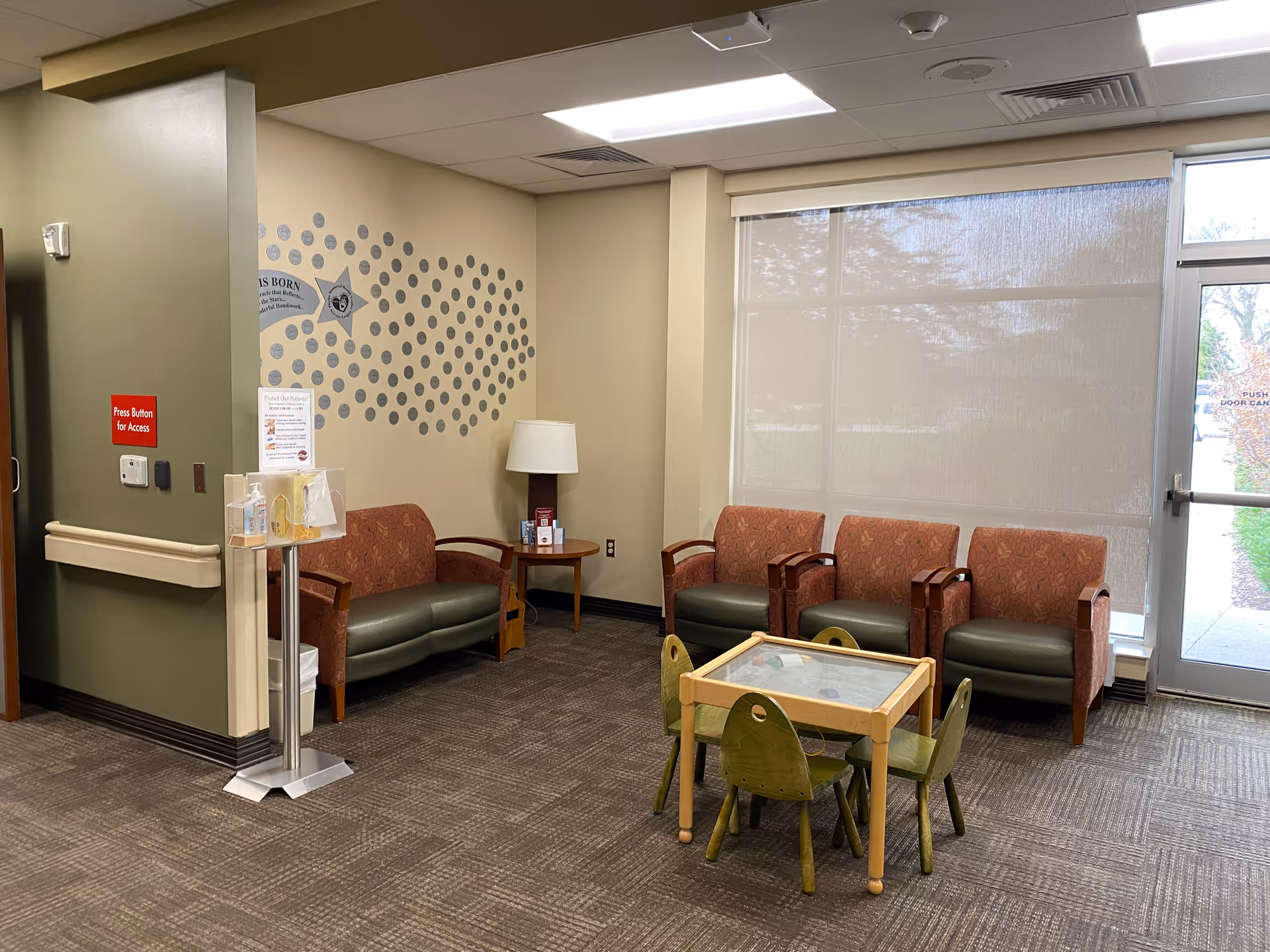 Interior waiting area with patterned wall, several chairs, and a small kid-sized table.