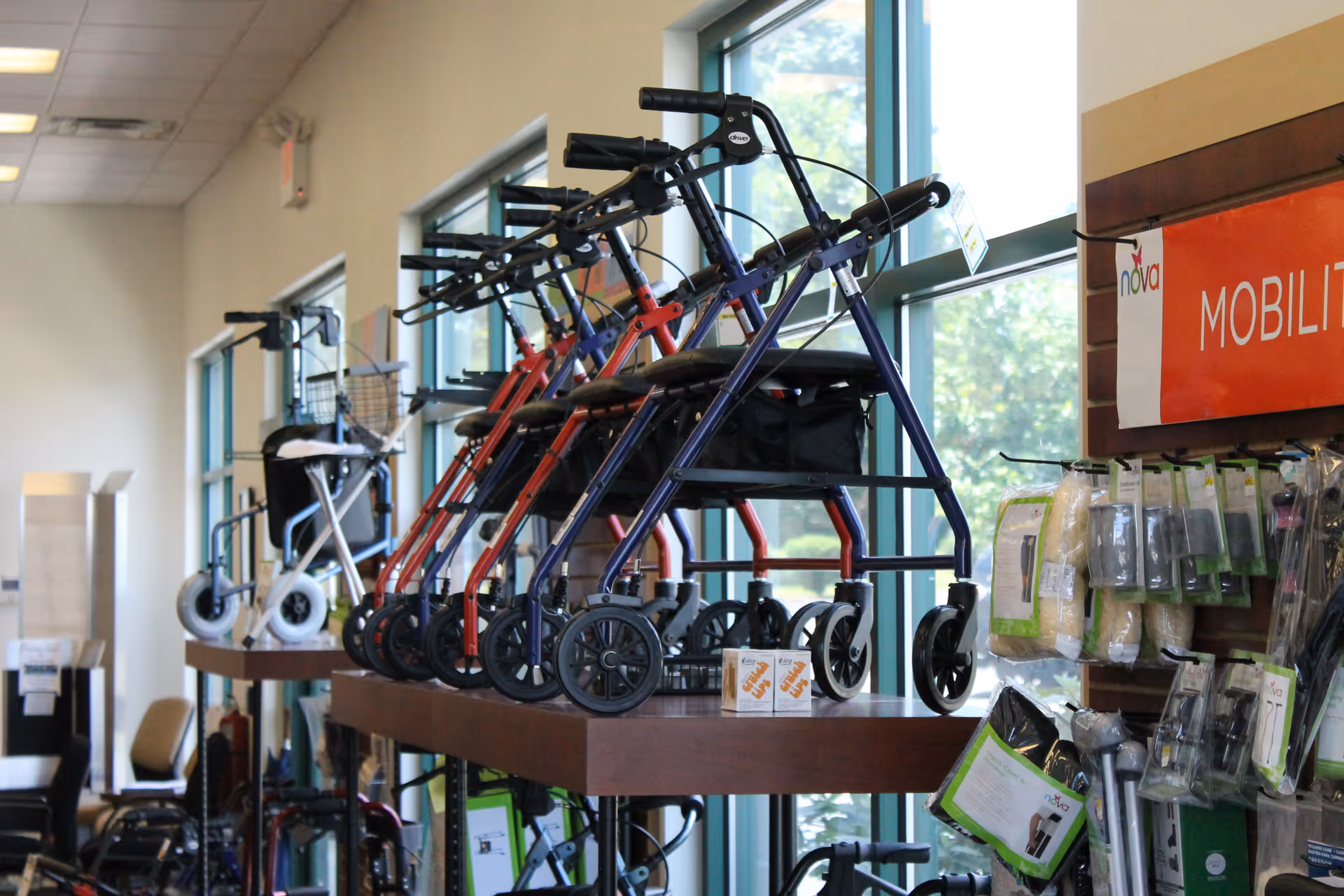 Inside a senior living facility showroom, multiple wheeled walkers and mobility devices on display.