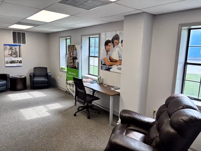 A quiet interior lounge with leather recliners, a desk, and posters.