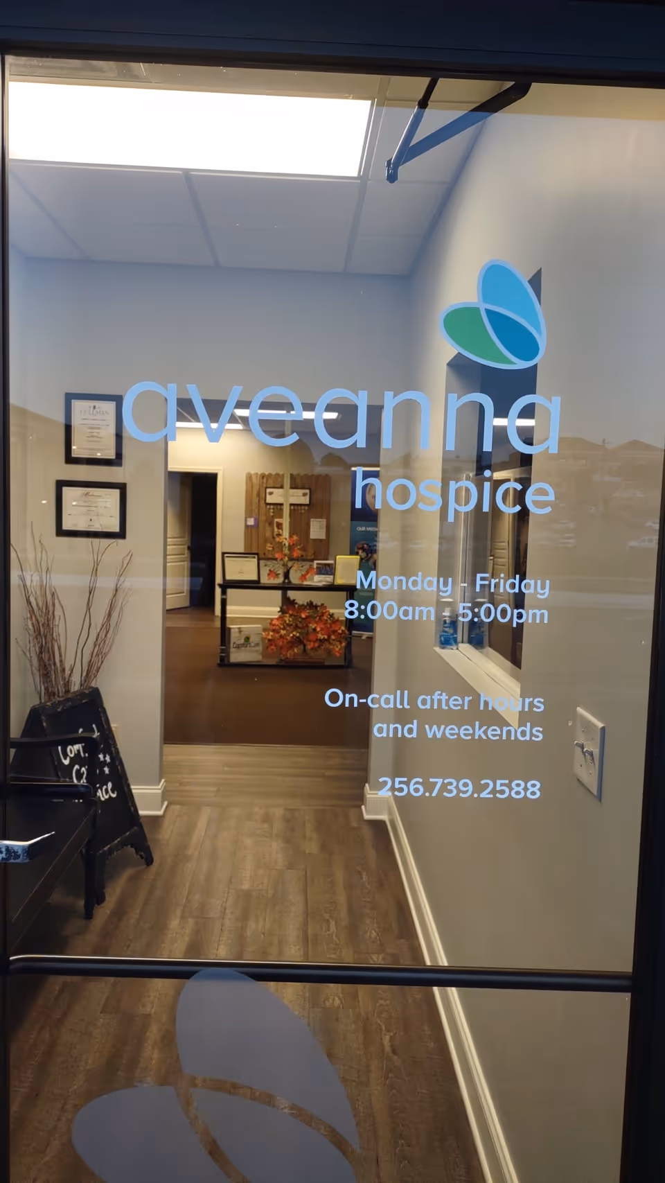 Glass entrance door with Aveanna Hospice logo, interior hallway and framed certificates visible.