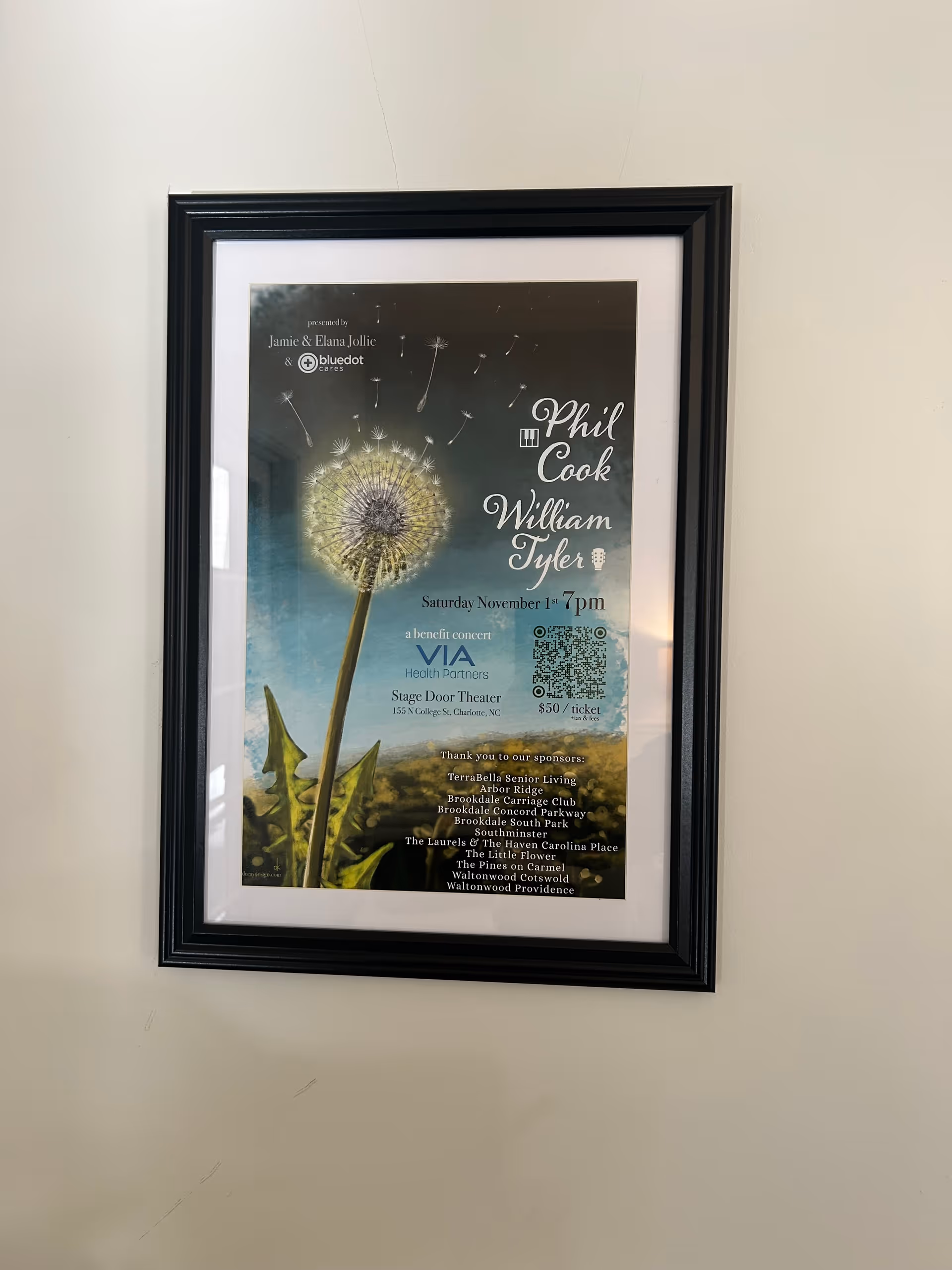 Framed poster on a light wall featuring a dandelion and event details.