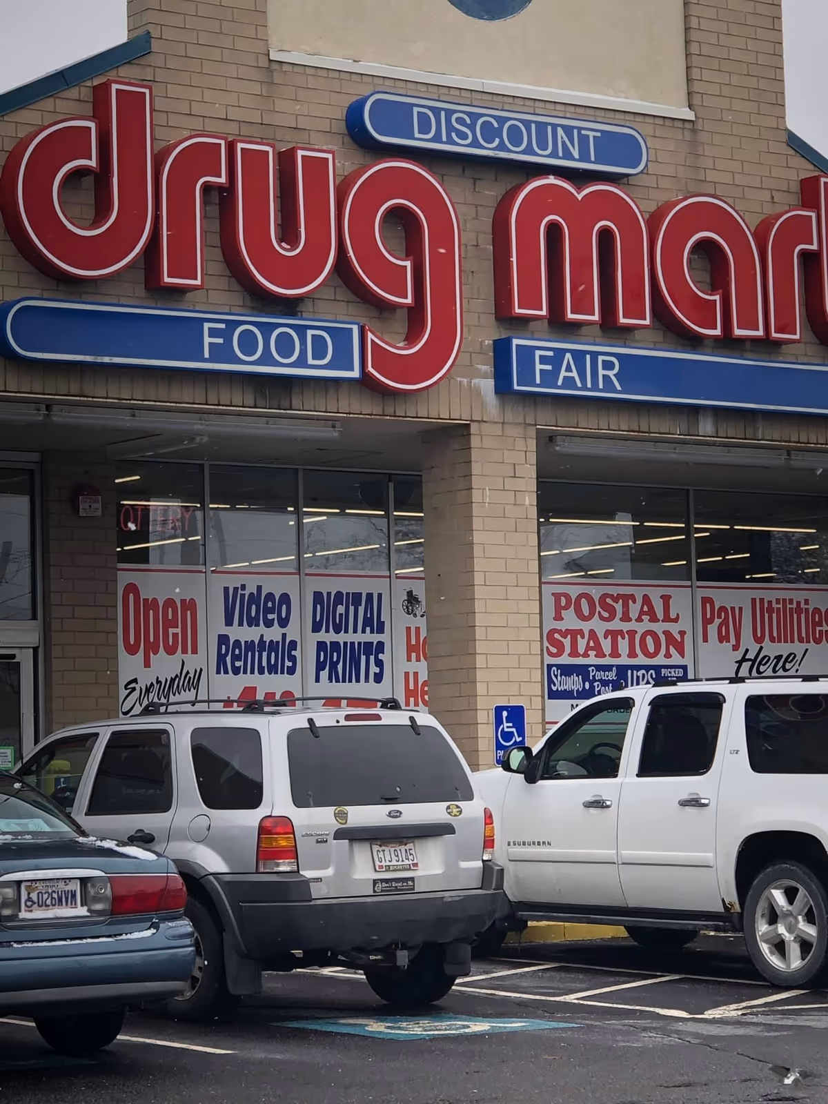 Facade of Discount Drug Mart storefront with several parked cars in front.