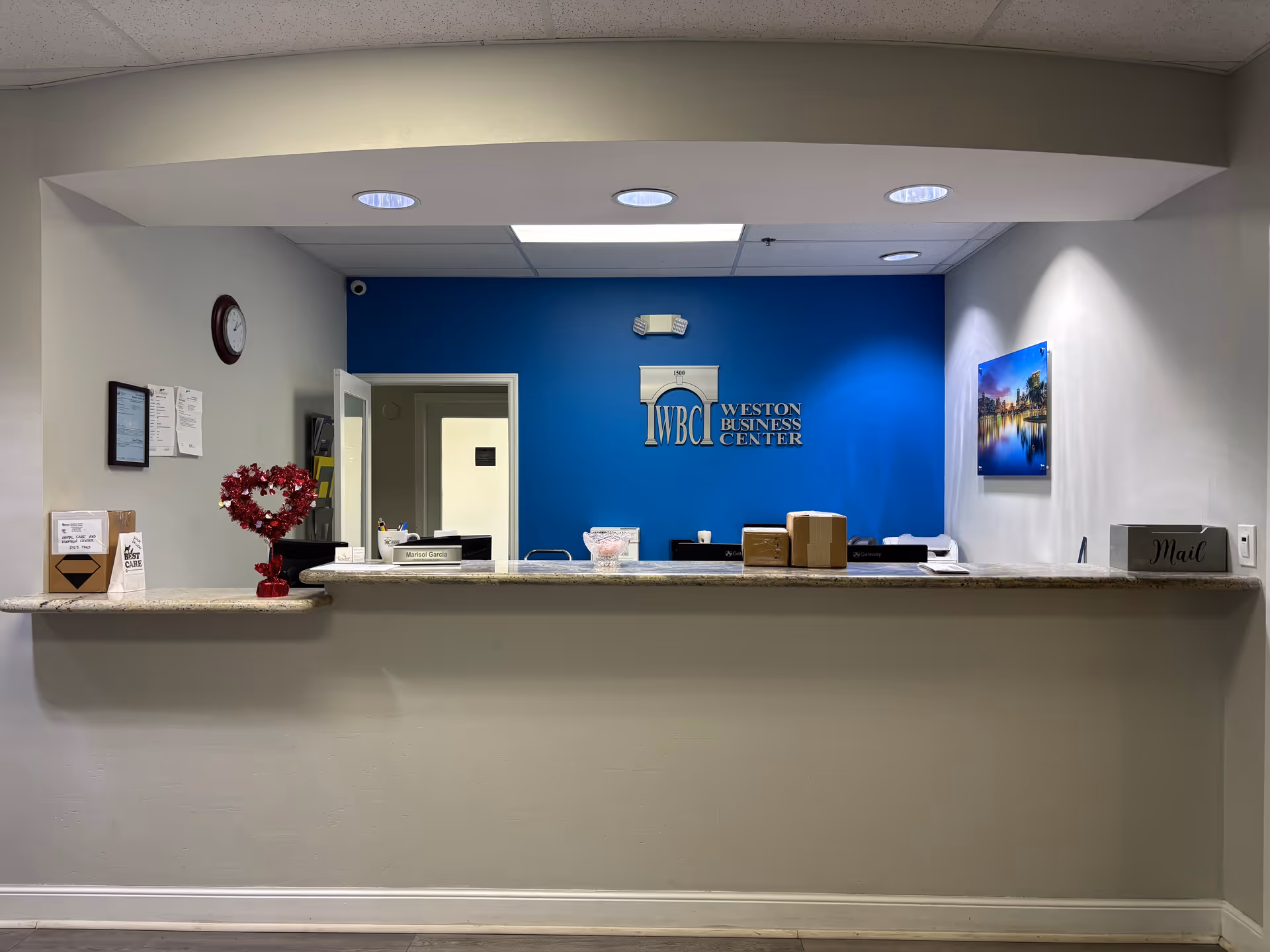Reception desk in a lobby with a blue wall featuring a Weston Business Center logo.