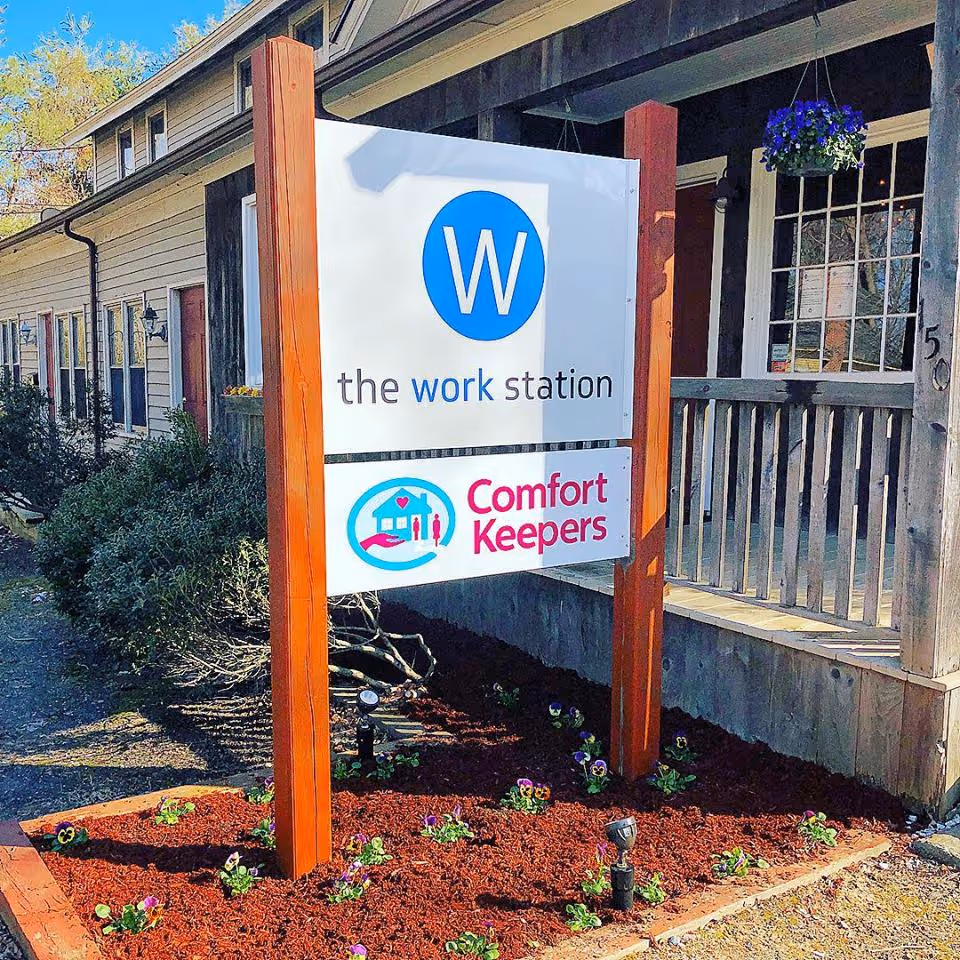 Exterior view of a building with a Comfort Keepers sign and decorative flowers.