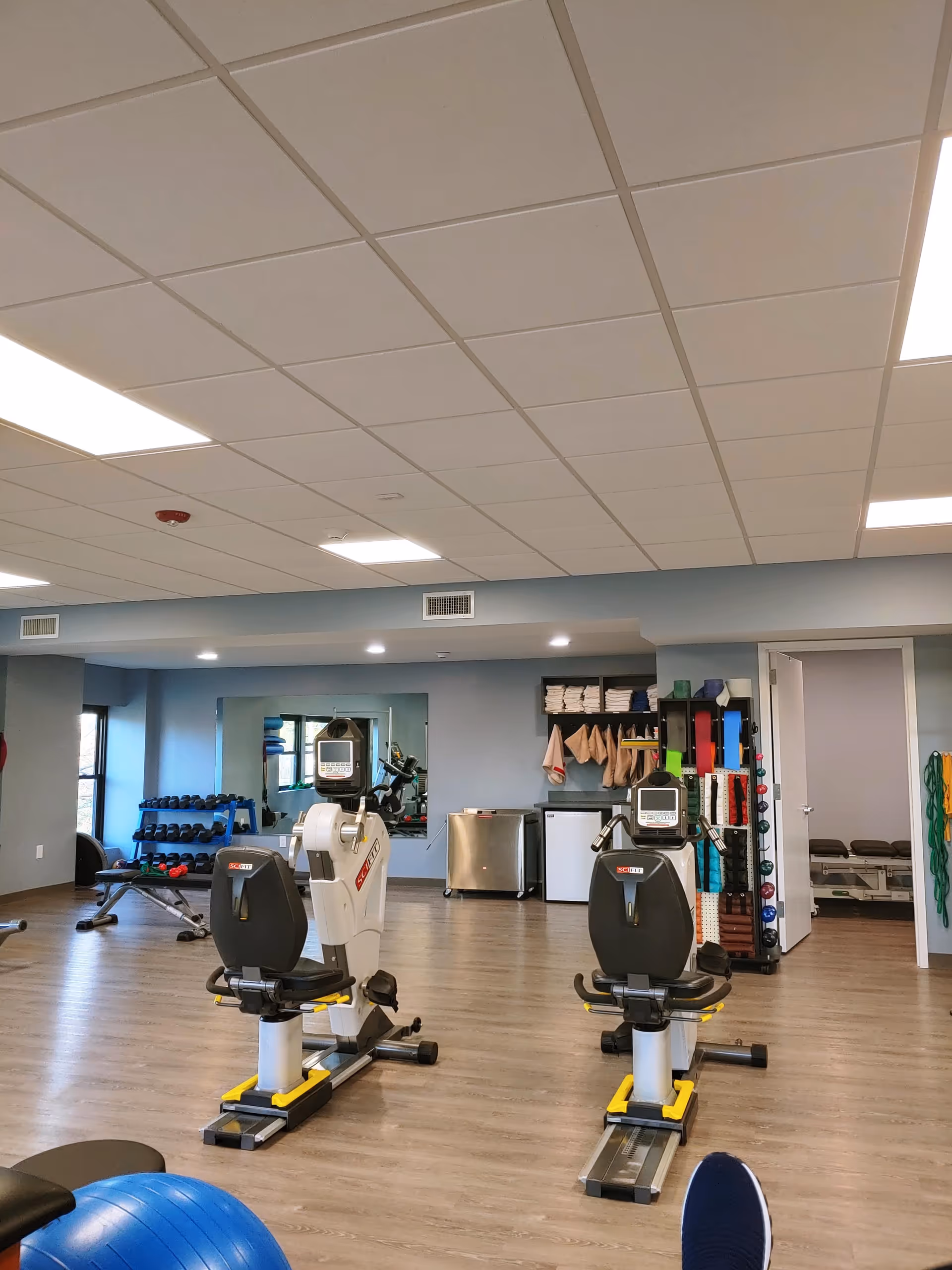 Bright indoor gym in a senior living facility featuring cardio machines, free weights, and organized storage.