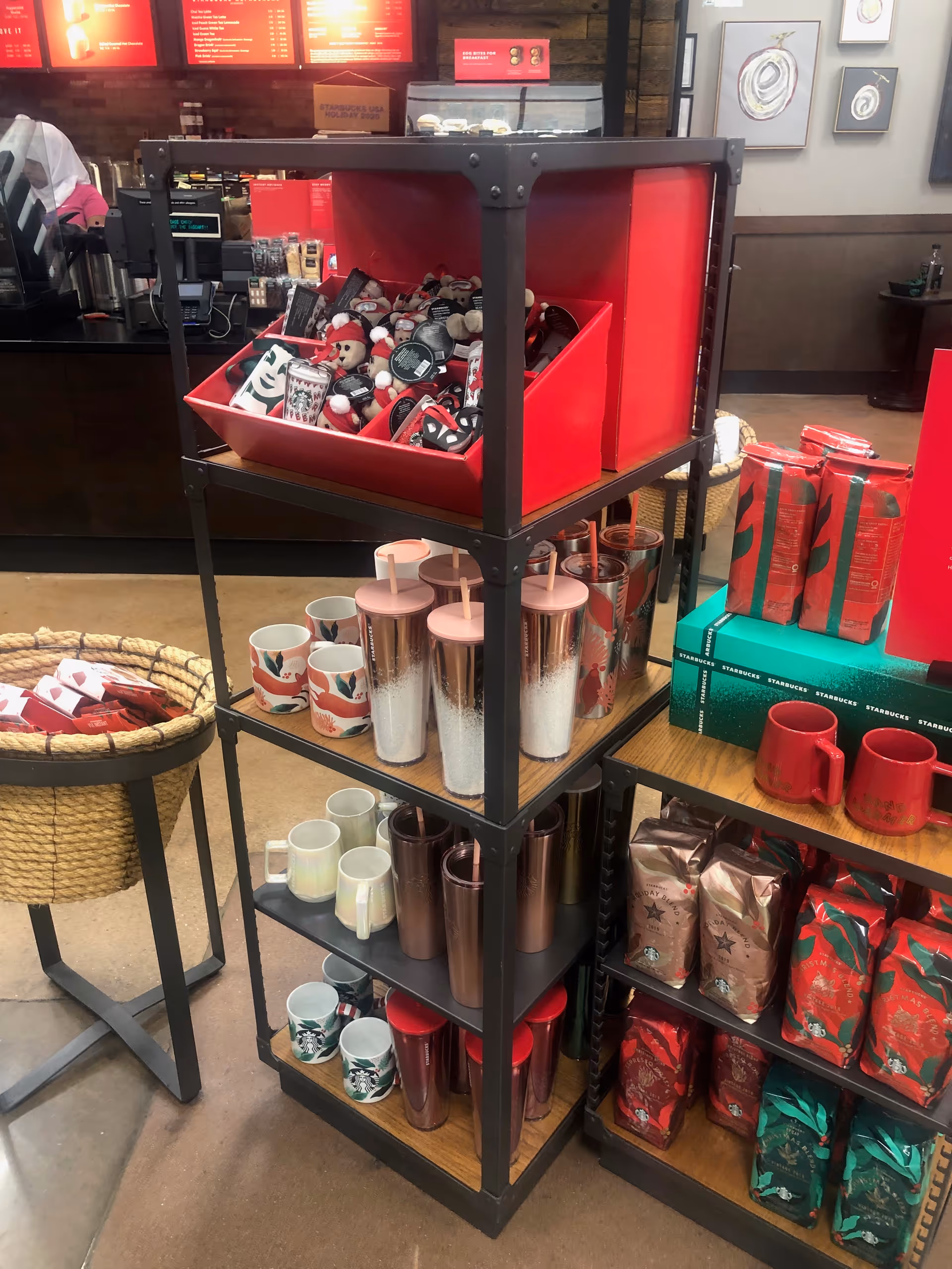 Shelving unit displays red gift items, mugs, tumblers, and wrapped coffee gifts in a Kroger store.