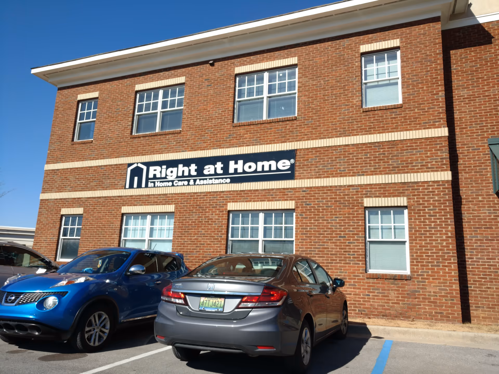 Brick-front building with Right at Home sign and parked cars in foreground