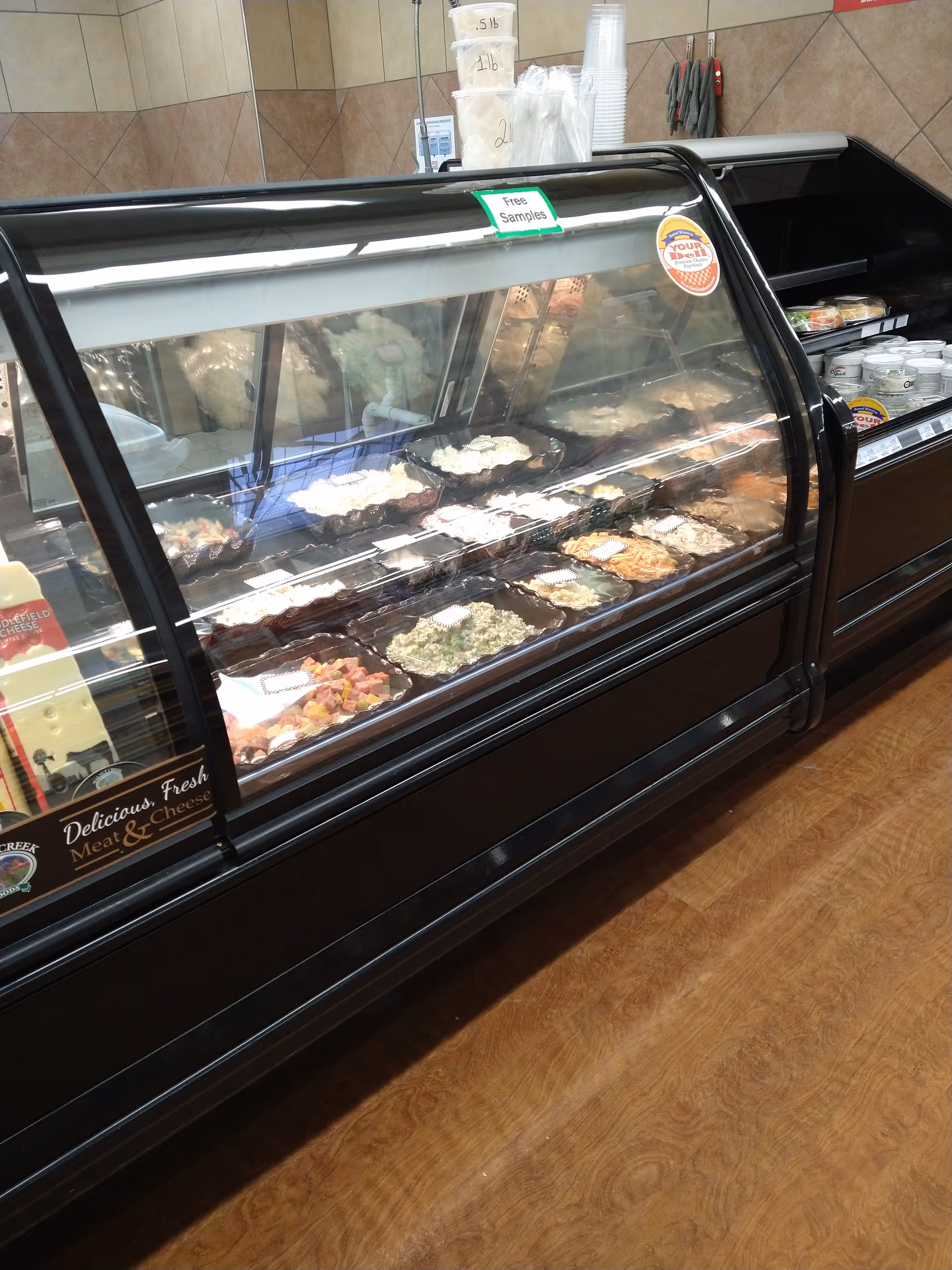 Glass refrigerated display case with assorted meats and cheeses inside Discount Drug Mart.