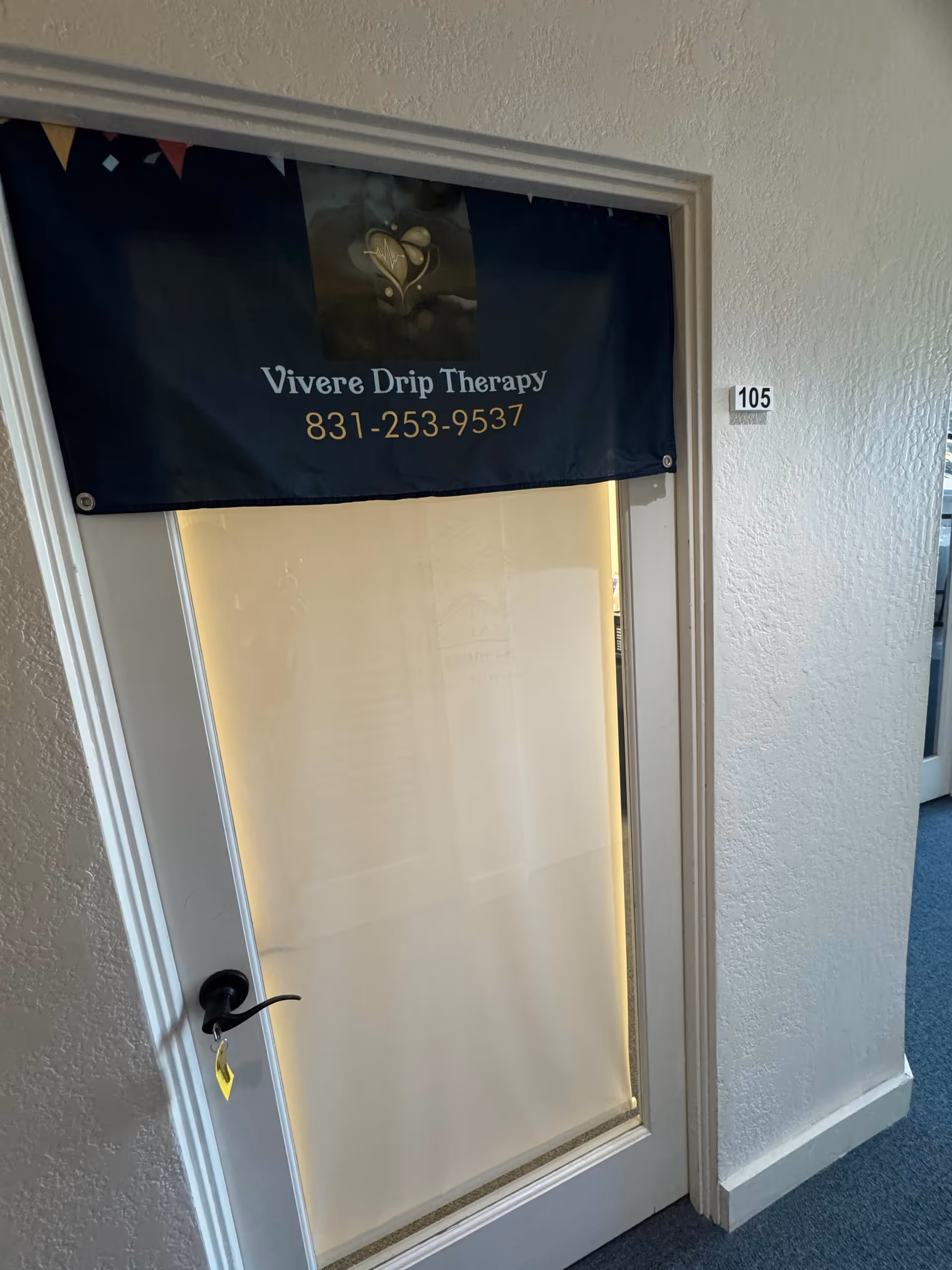 Door in hallway with Vivere Drip Therapy banner and room 105.