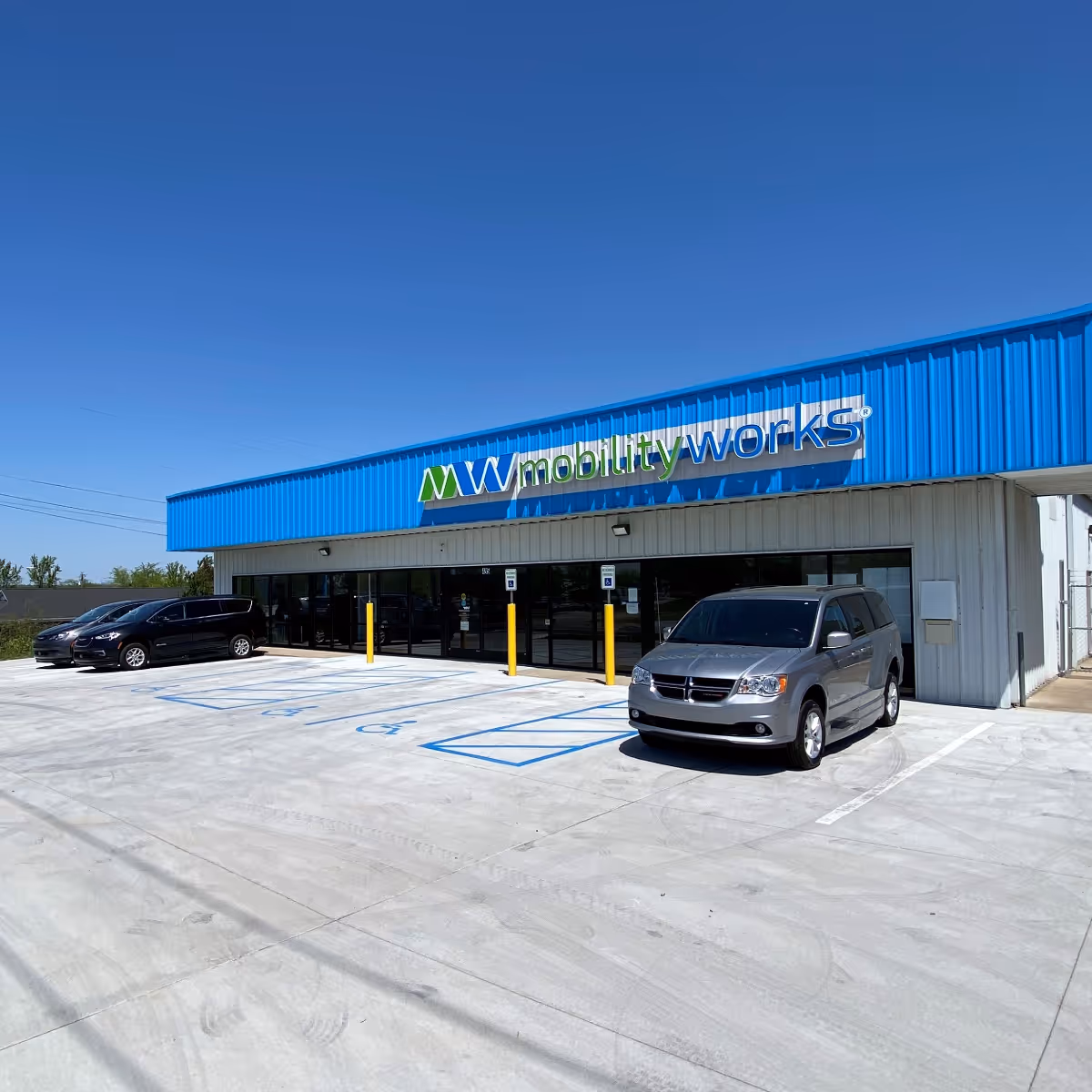 Blue MobilityWorks storefront with a sign, glass doors, and parked cars.